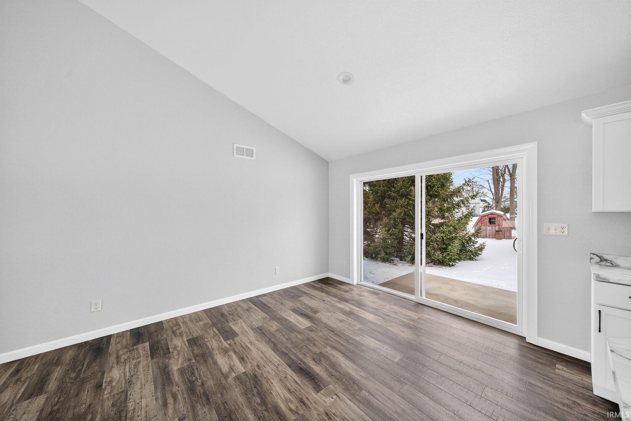 Unfurnished dining area with dark wood finished floors and lofted ceiling