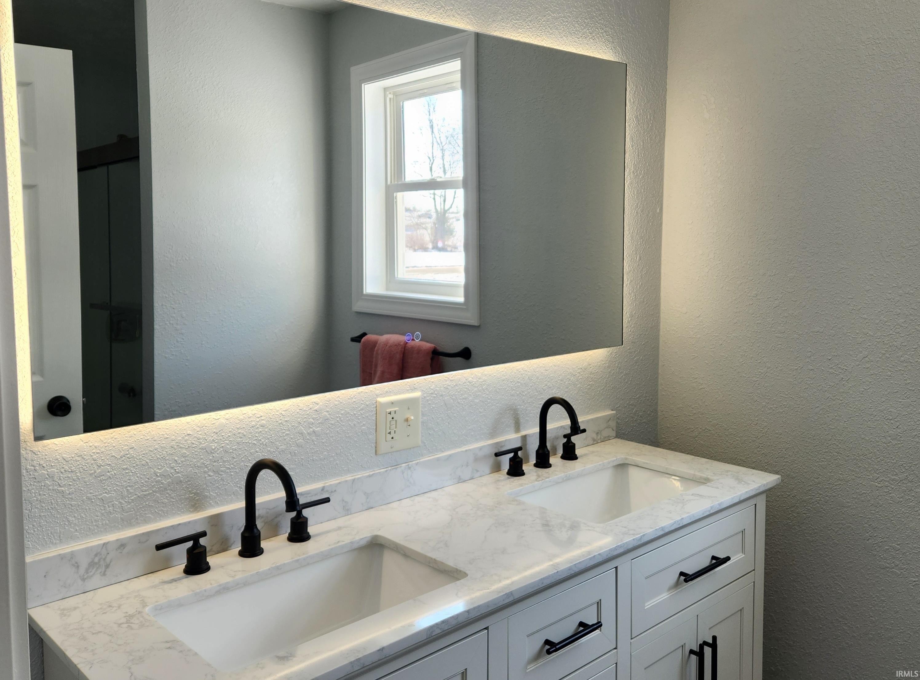 Bathroom with a textured wall and double vanity