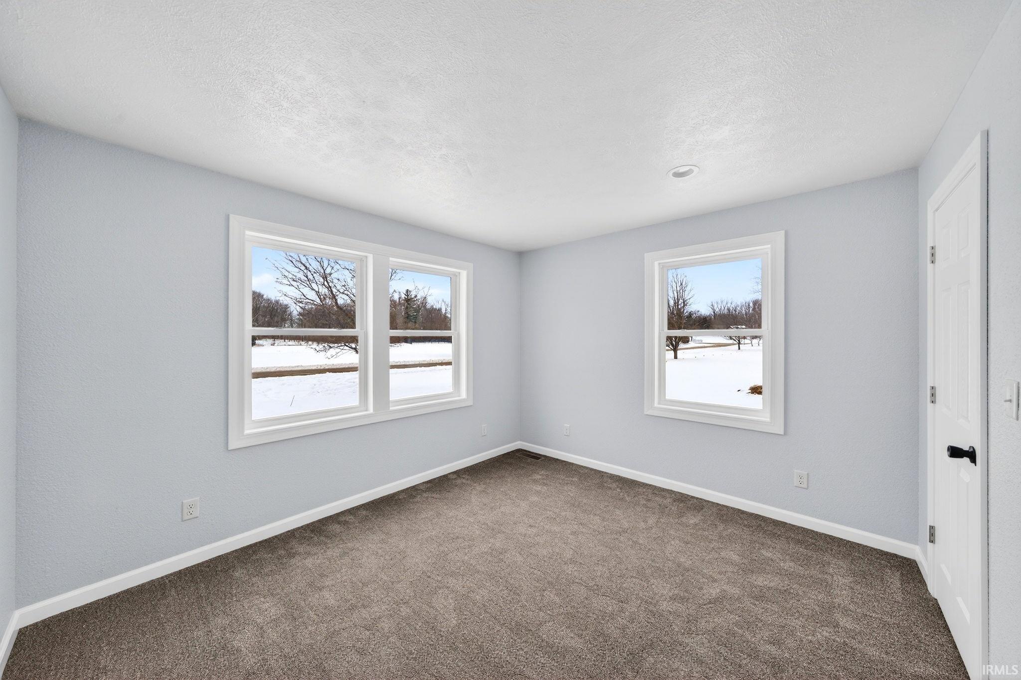 Unfurnished room with dark colored carpet and a textured ceiling