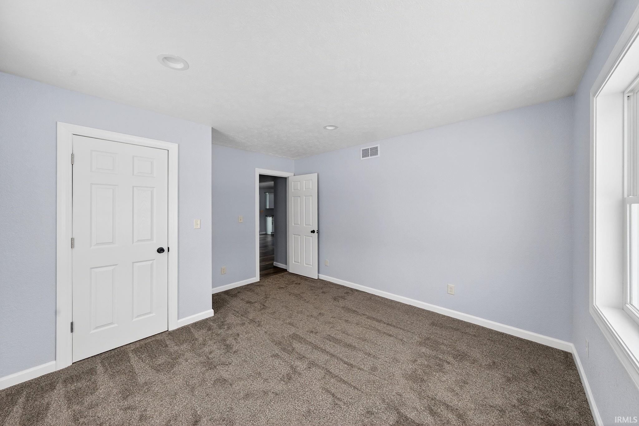 Unfurnished bedroom with carpet flooring and baseboards