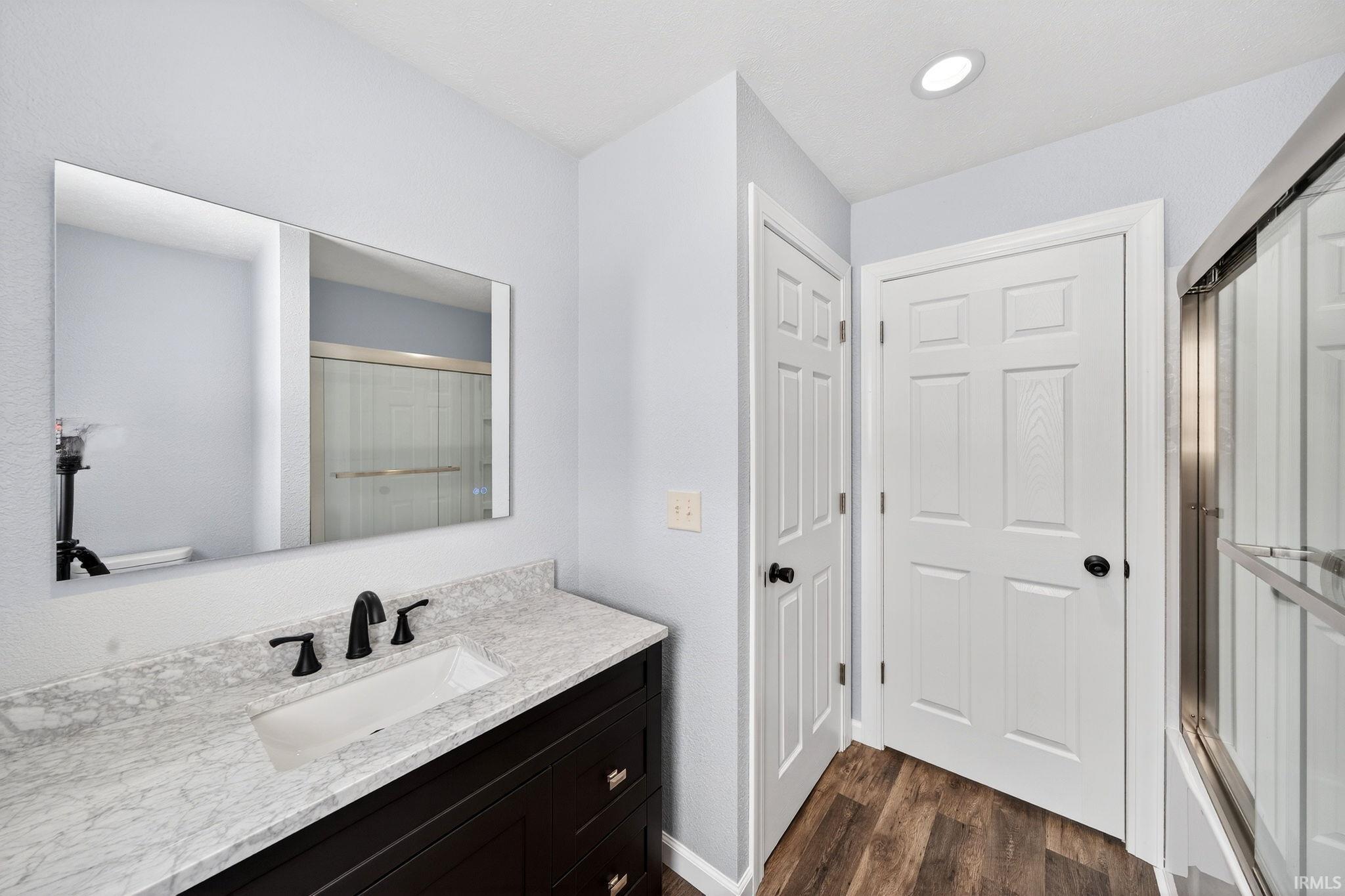 Bathroom with a shower with door, vanity, and dark wood-type flooring