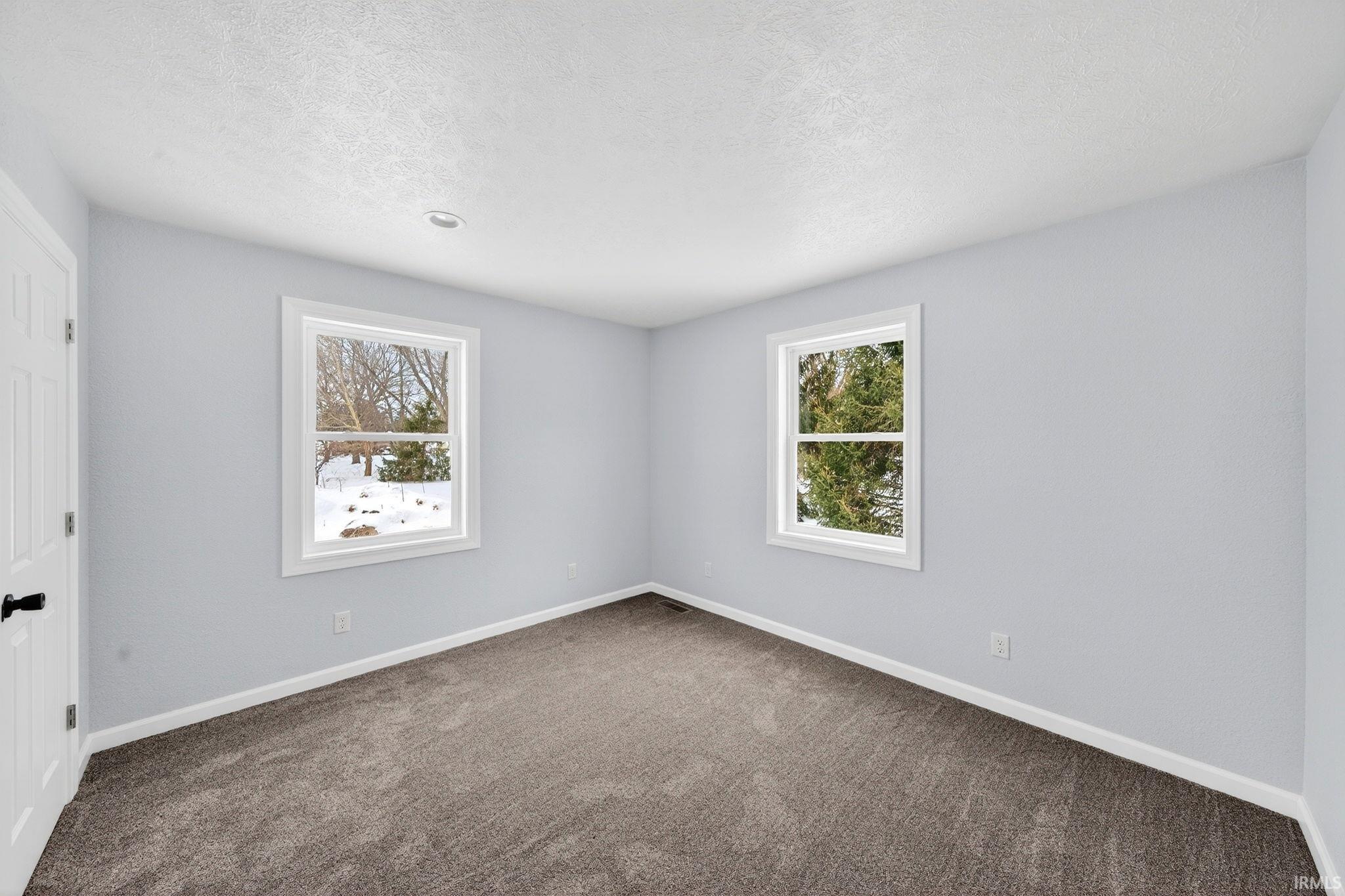 Spare room featuring dark colored carpet and a textured ceiling
