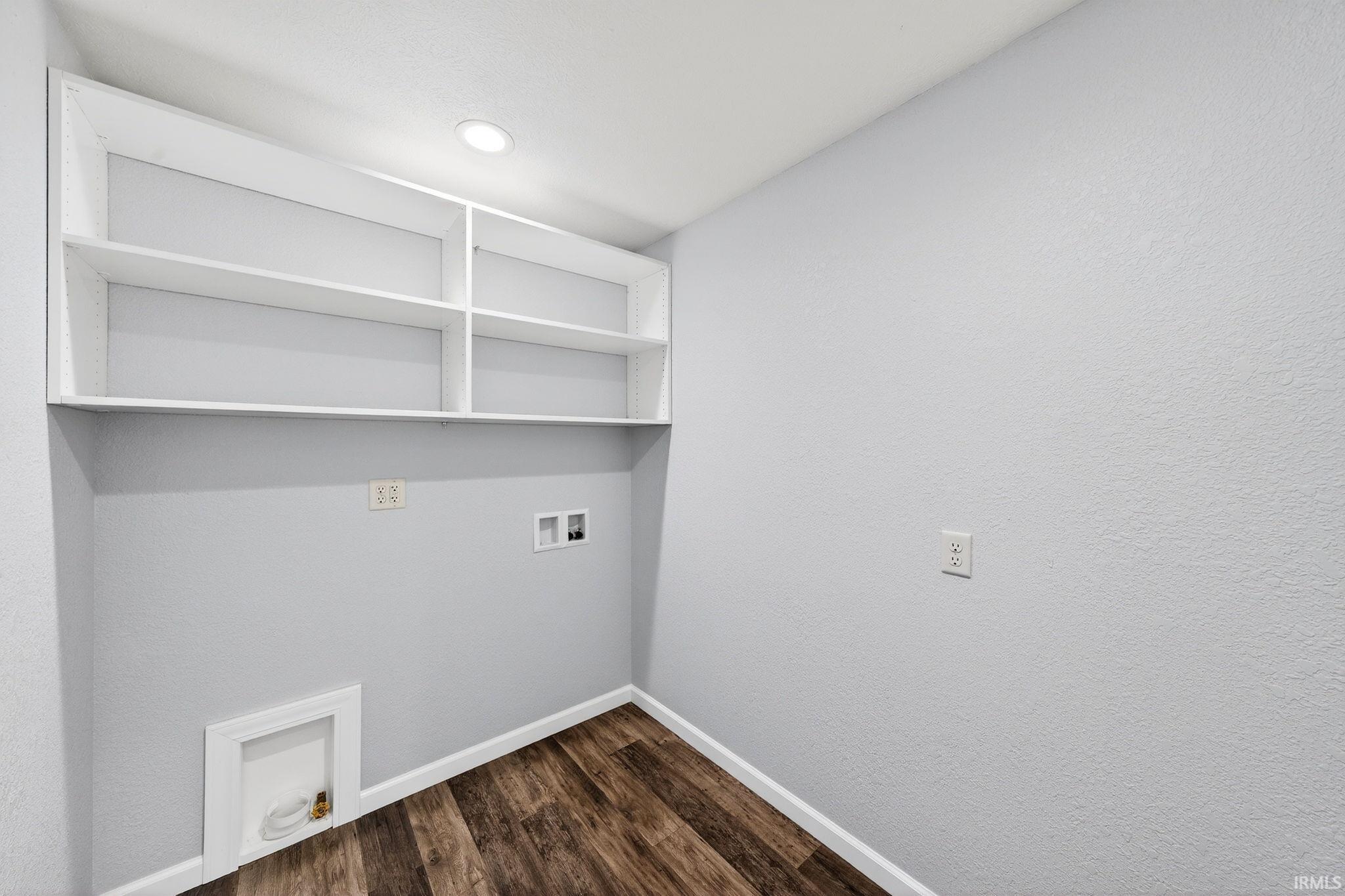Laundry room with washer hookup, dark wood-type flooring, and a textured wall