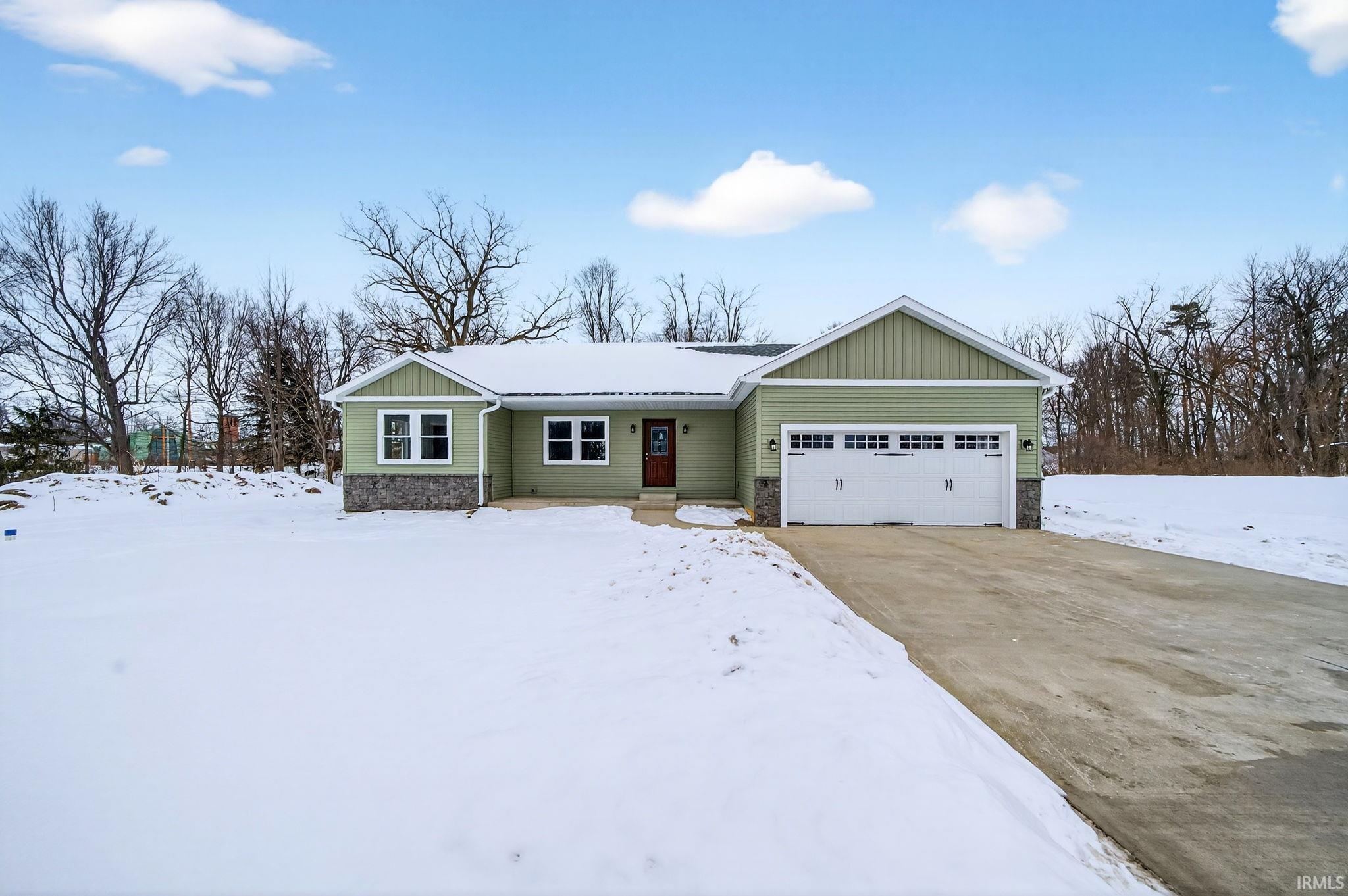Ranch-style house with an attached garage, concrete driveway, and stone siding
