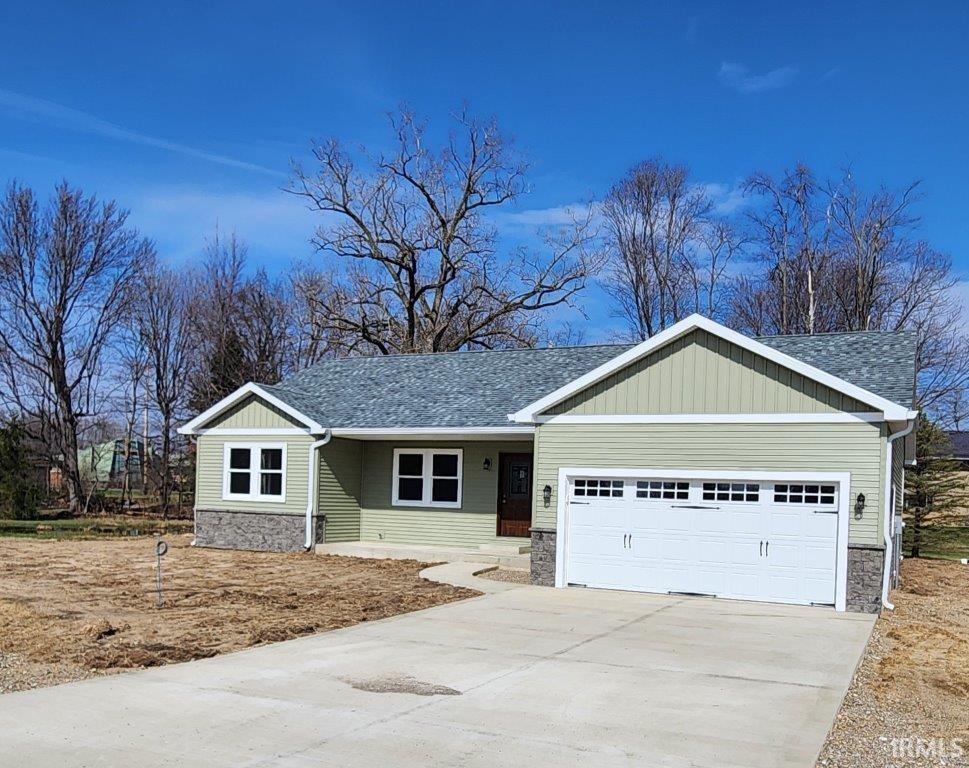 View of front of property with a porch, a garage, driveway, and stone siding