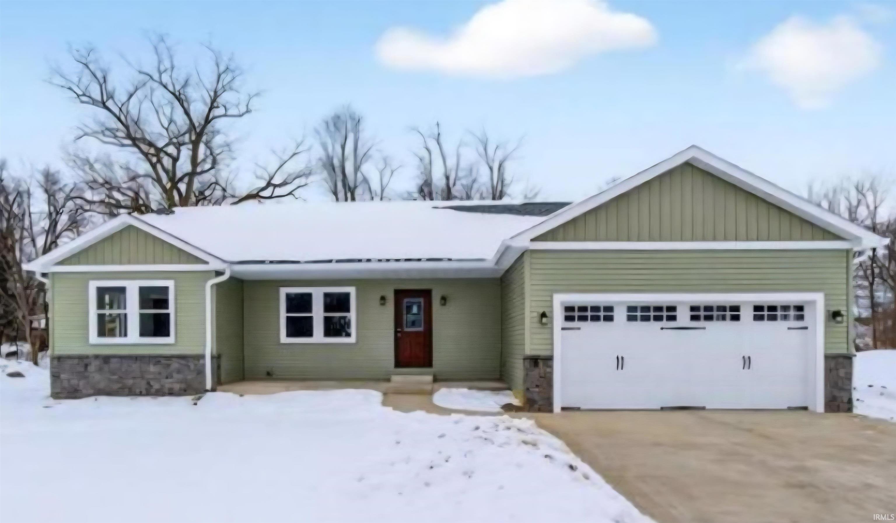 View of front of house with a garage, stone siding, board and batten siding, and concrete driveway