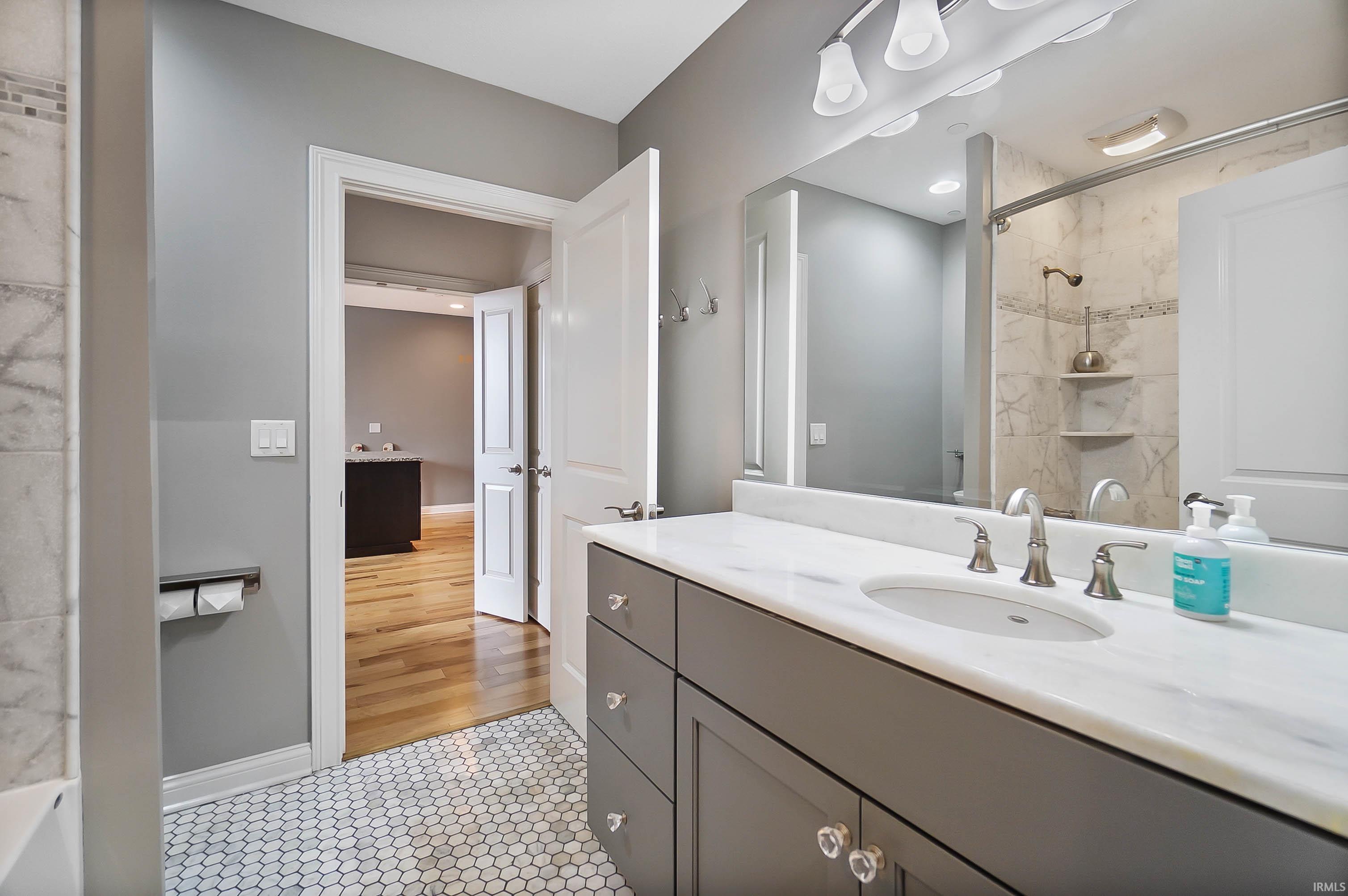 Bathroom featuring a tile shower, vanity, and light tile patterned floors