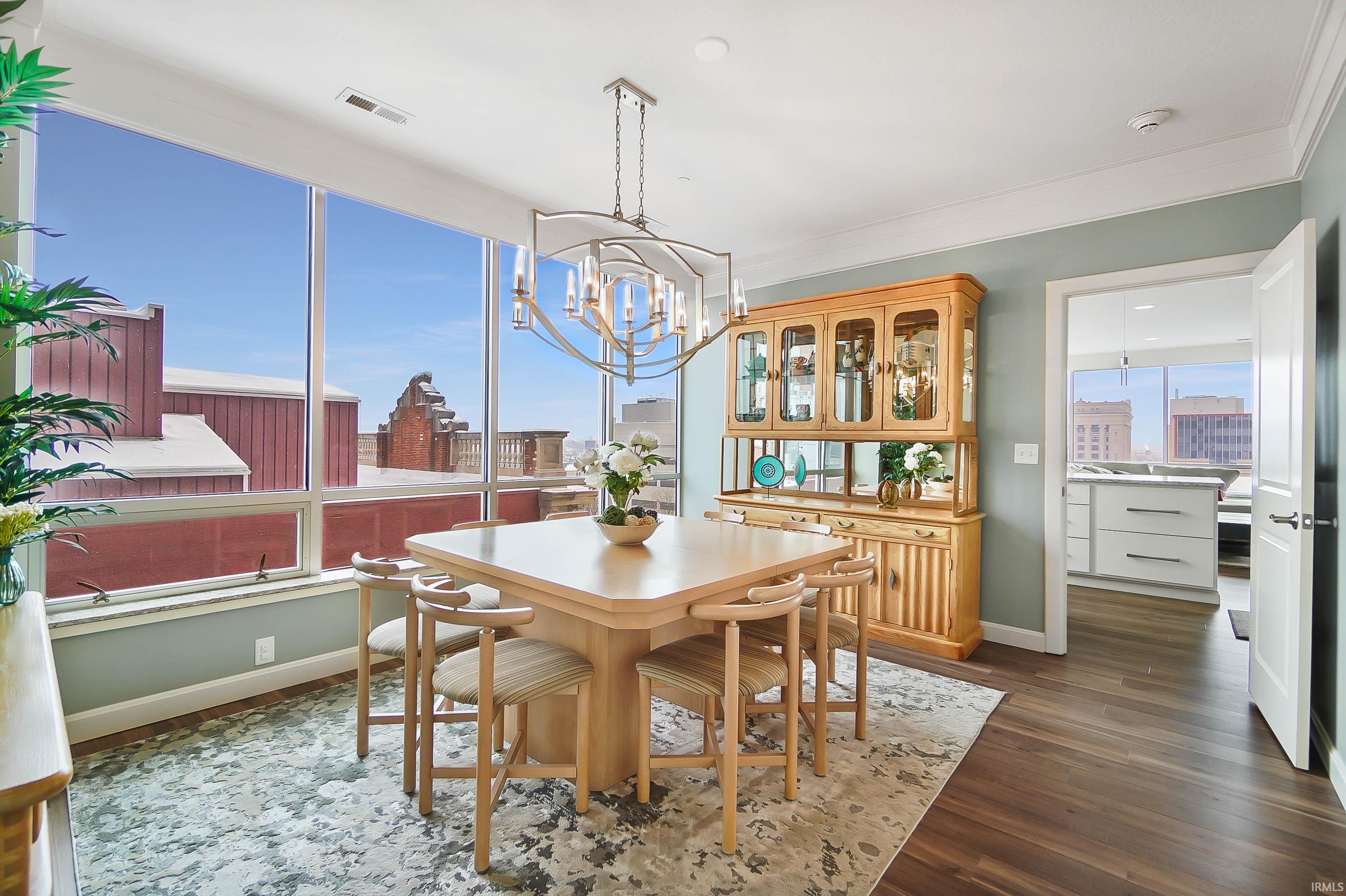 Dining area featuring dark wood-style flooring, a chandelier, and ornamental molding