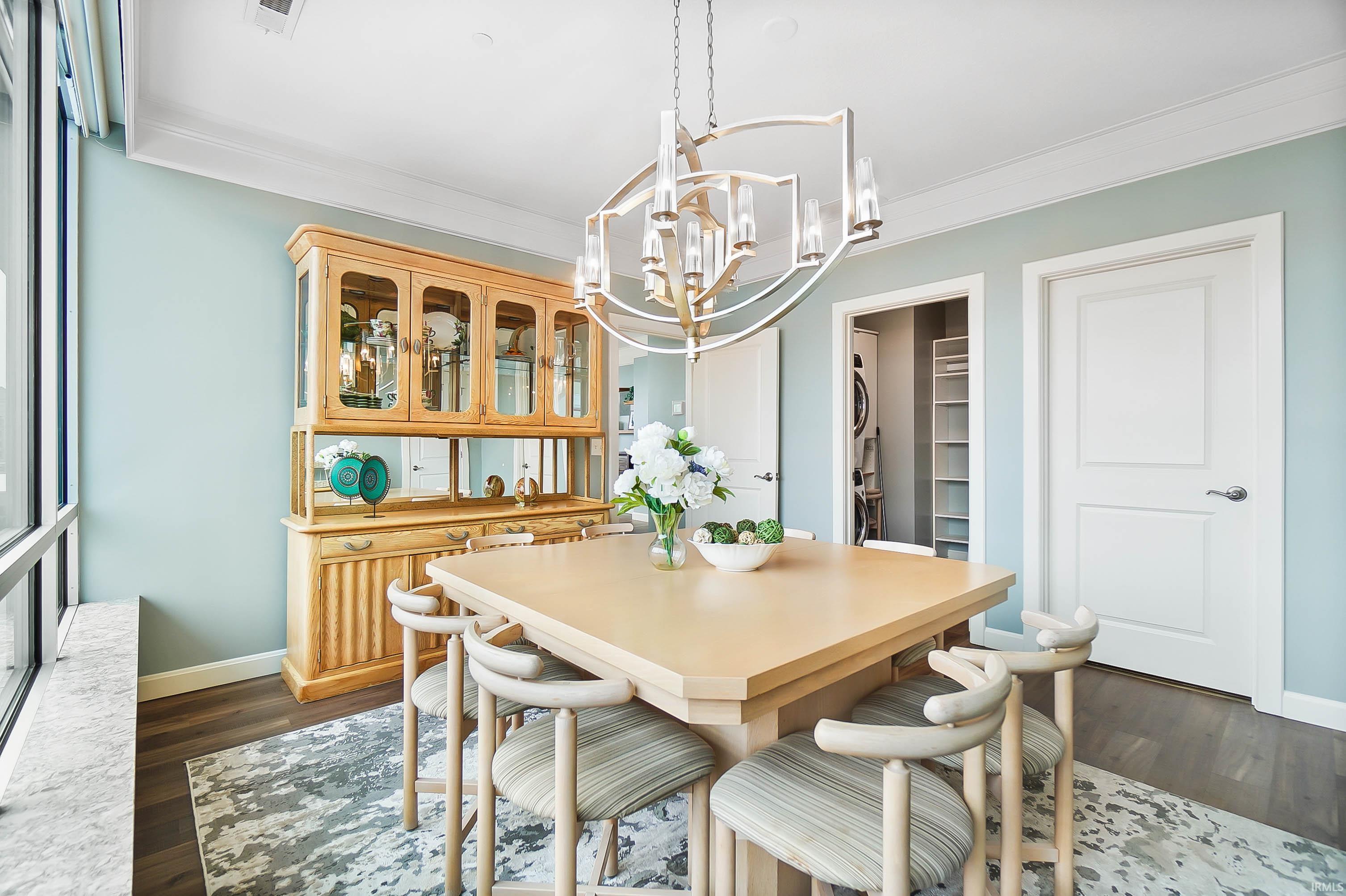 Dining area with ornamental molding, dark wood-style flooring, and a chandelier