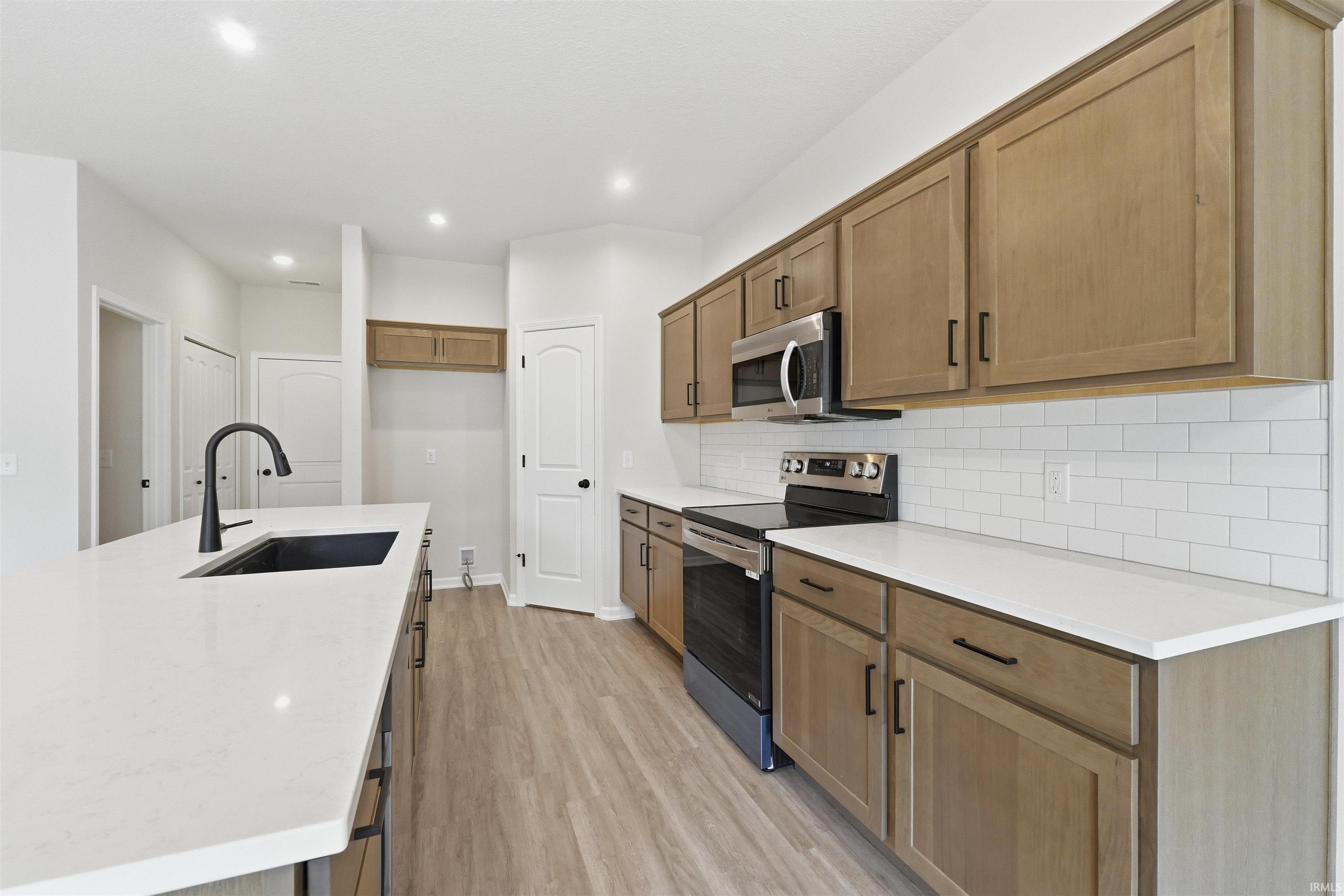 Modern kitchen with light wood-finish cabinetry and white countertops