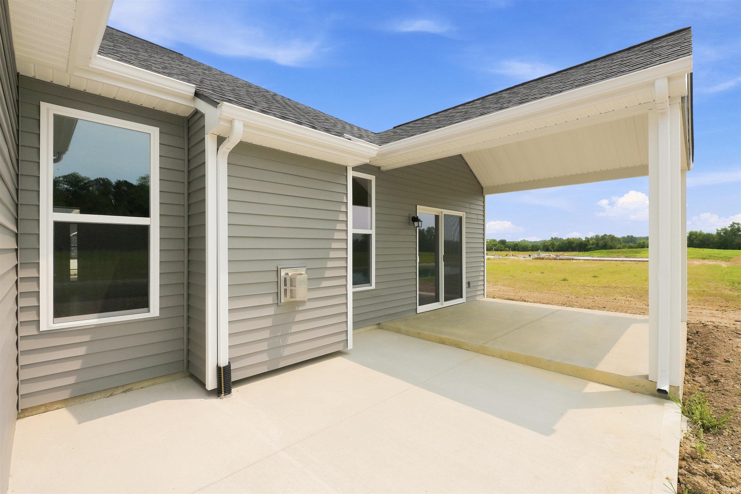 Covered patio with concrete flooring, gray siding, white trim, and sliding glass doors