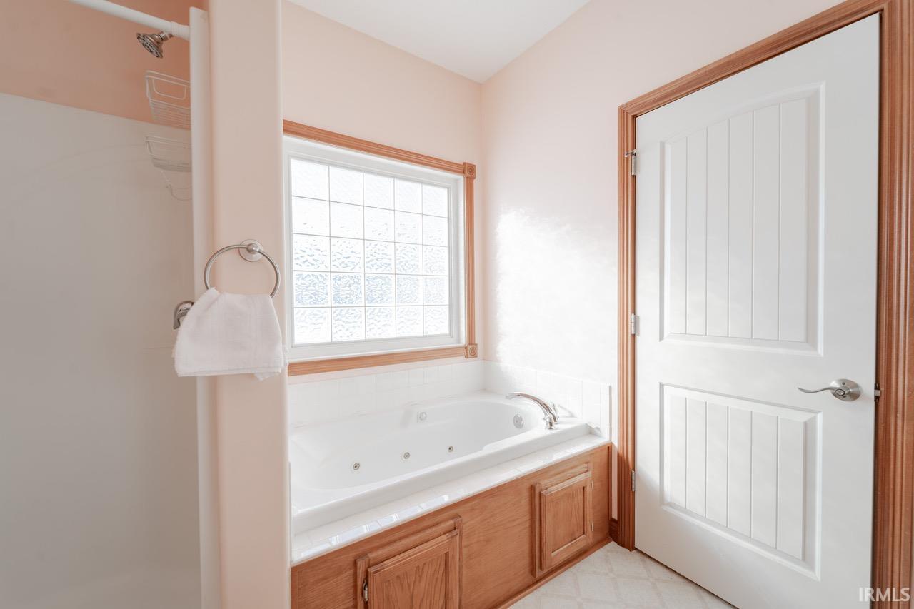 Bathroom with a tub with jets and light floors