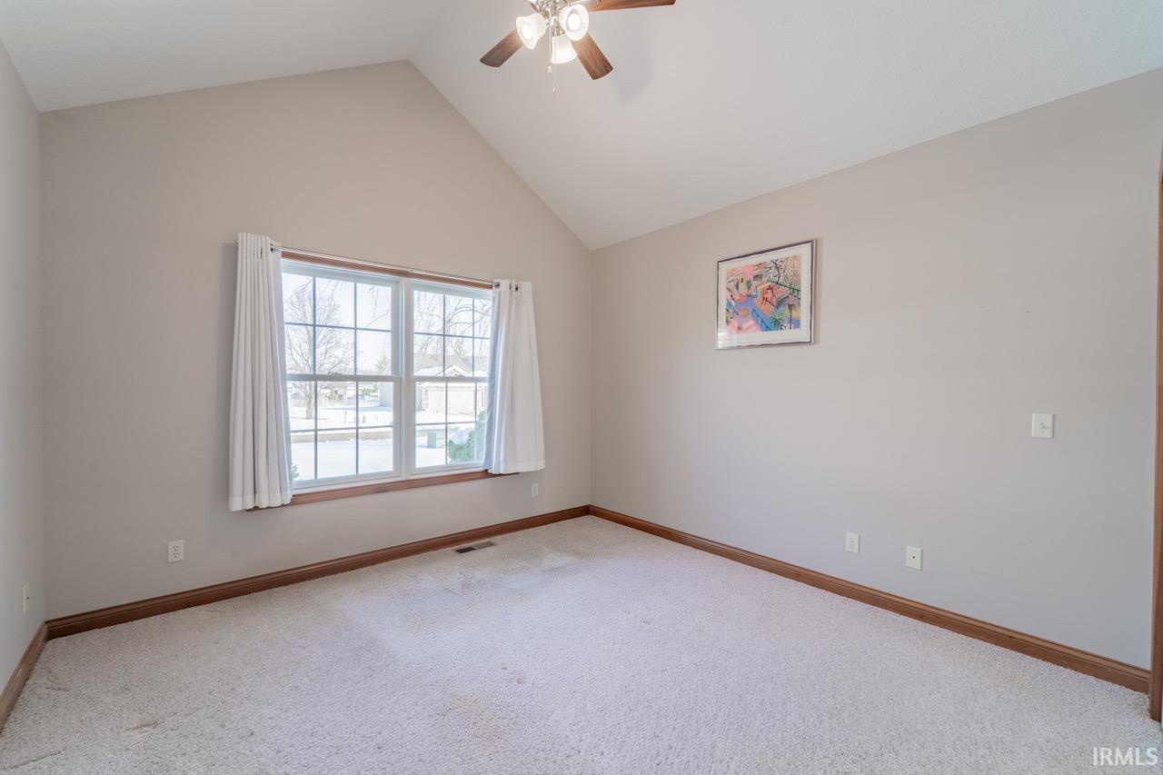 Unfurnished room featuring a ceiling fan, carpet floors, and a high ceiling