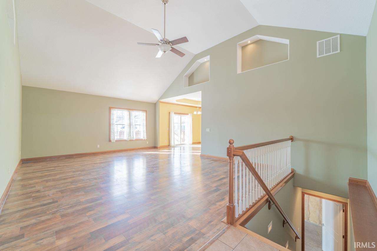 Spare room featuring a high ceiling, wood finished floors, and a ceiling fan