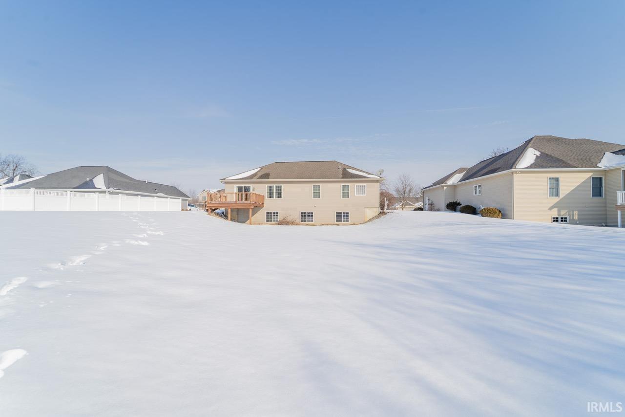 Snowy yard featuring a residential view and a wooden deck