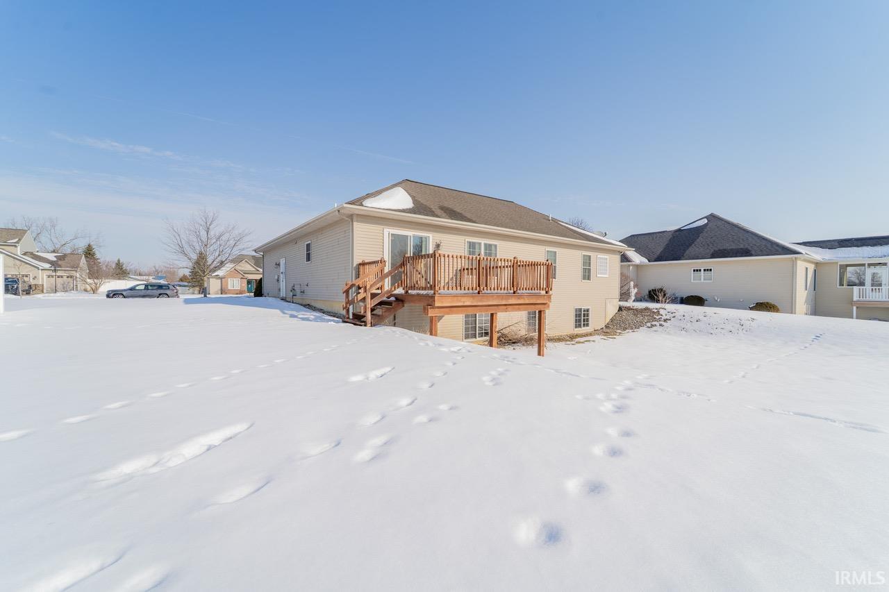 Snow covered rear of property featuring a deck