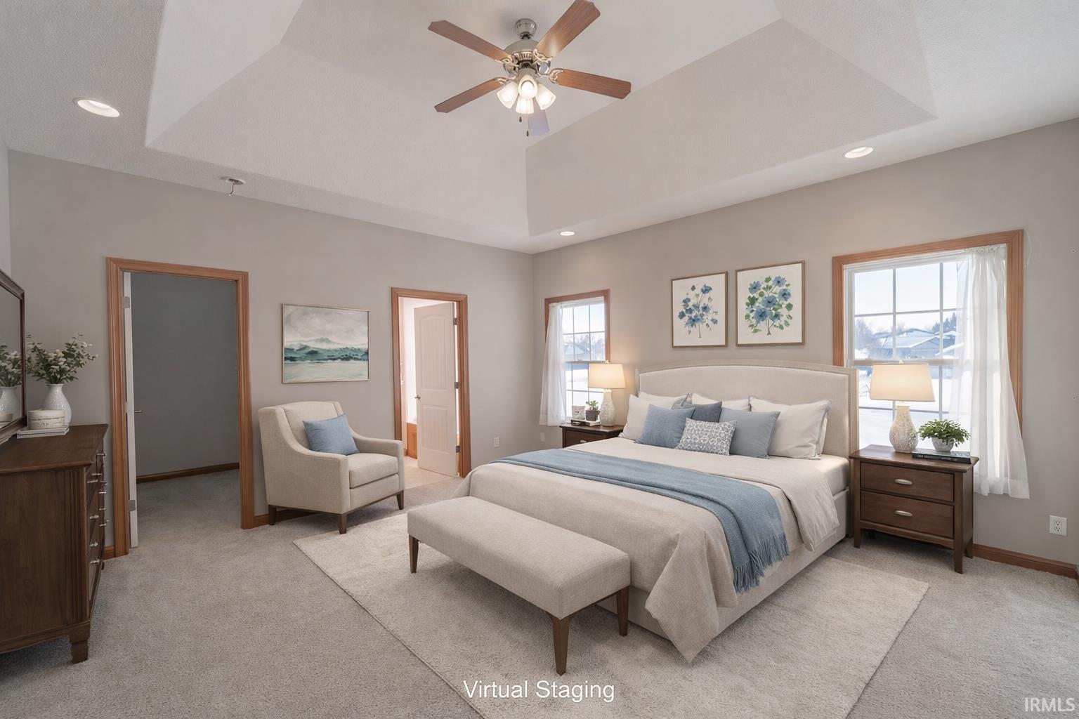 Bedroom with light colored carpet, recessed lighting, ceiling fan, a raised ceiling, and ensuite bath