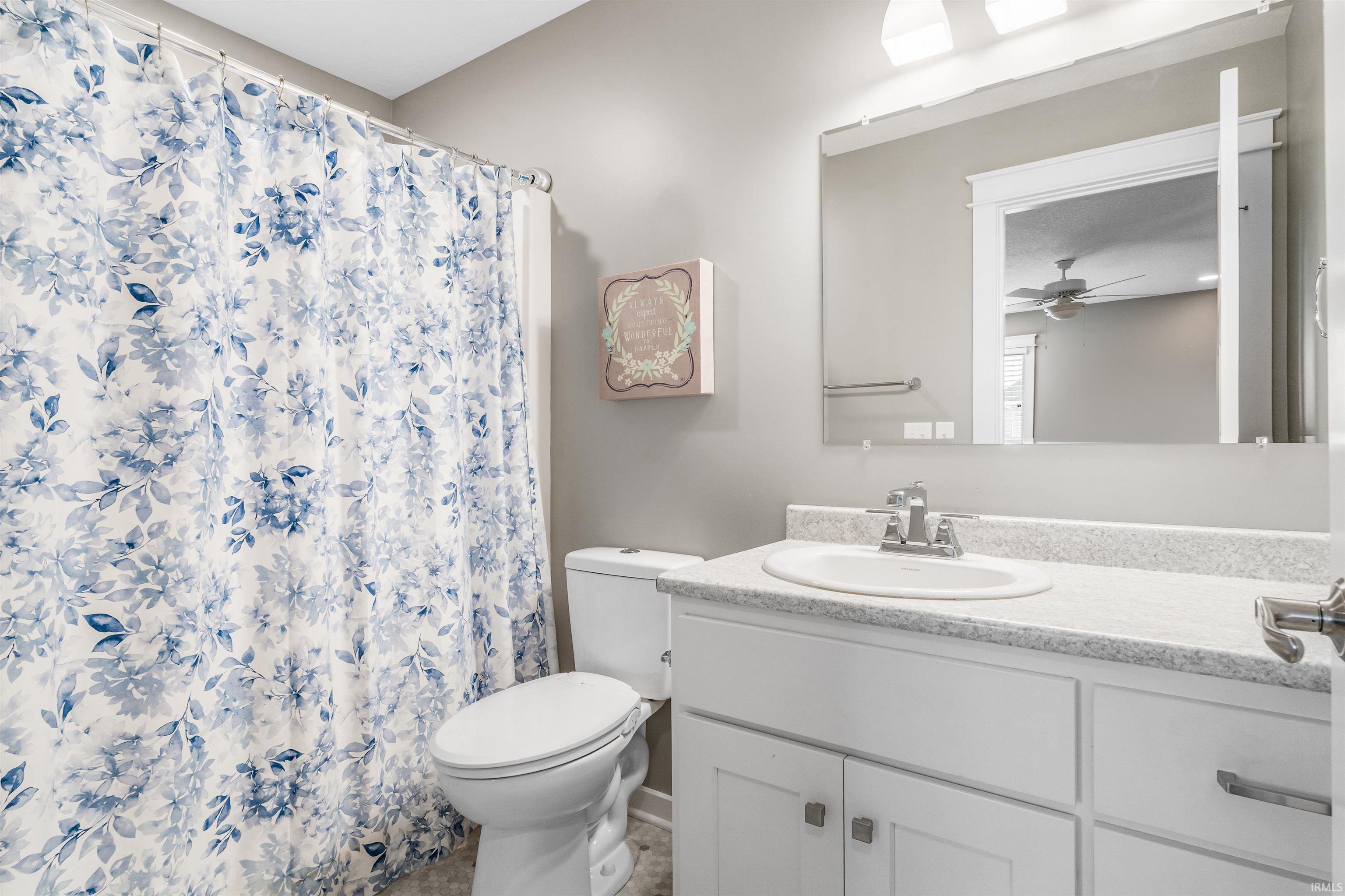 Bathroom with vanity, curtained shower, and a ceiling fan