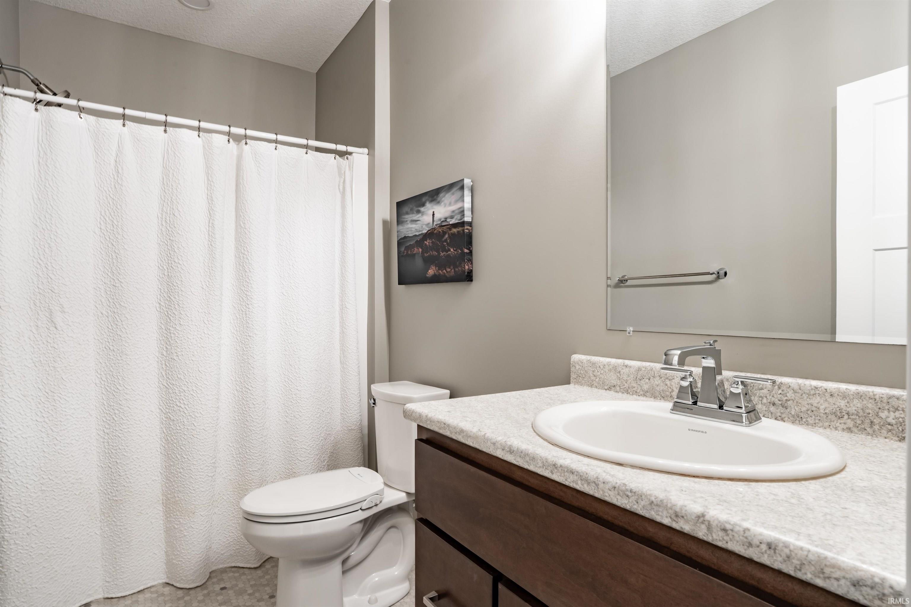 Bathroom with vanity, a shower with curtain, and a textured ceiling