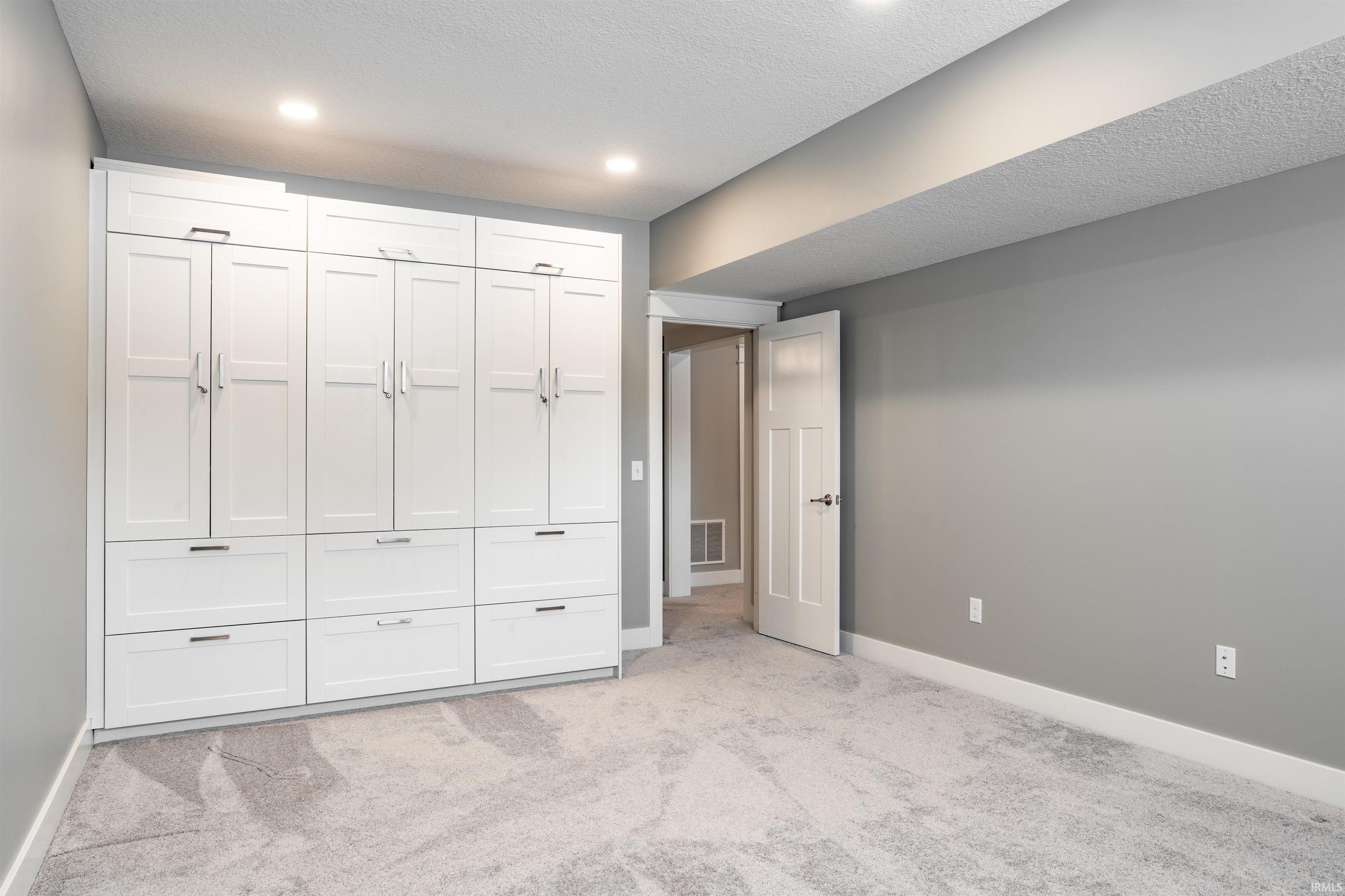 Unfurnished bedroom featuring light colored carpet, a textured ceiling, and a closet