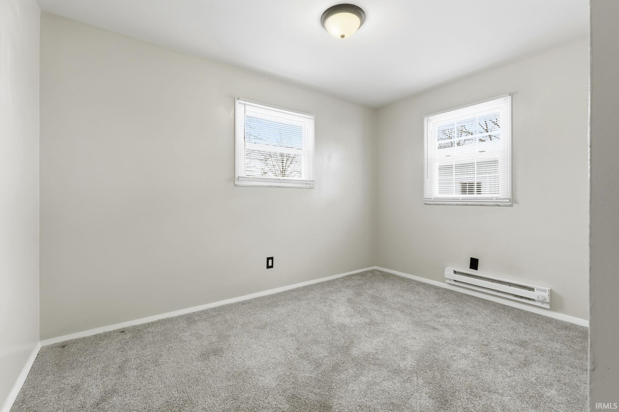 Carpeted spare room with baseboard heating and baseboards