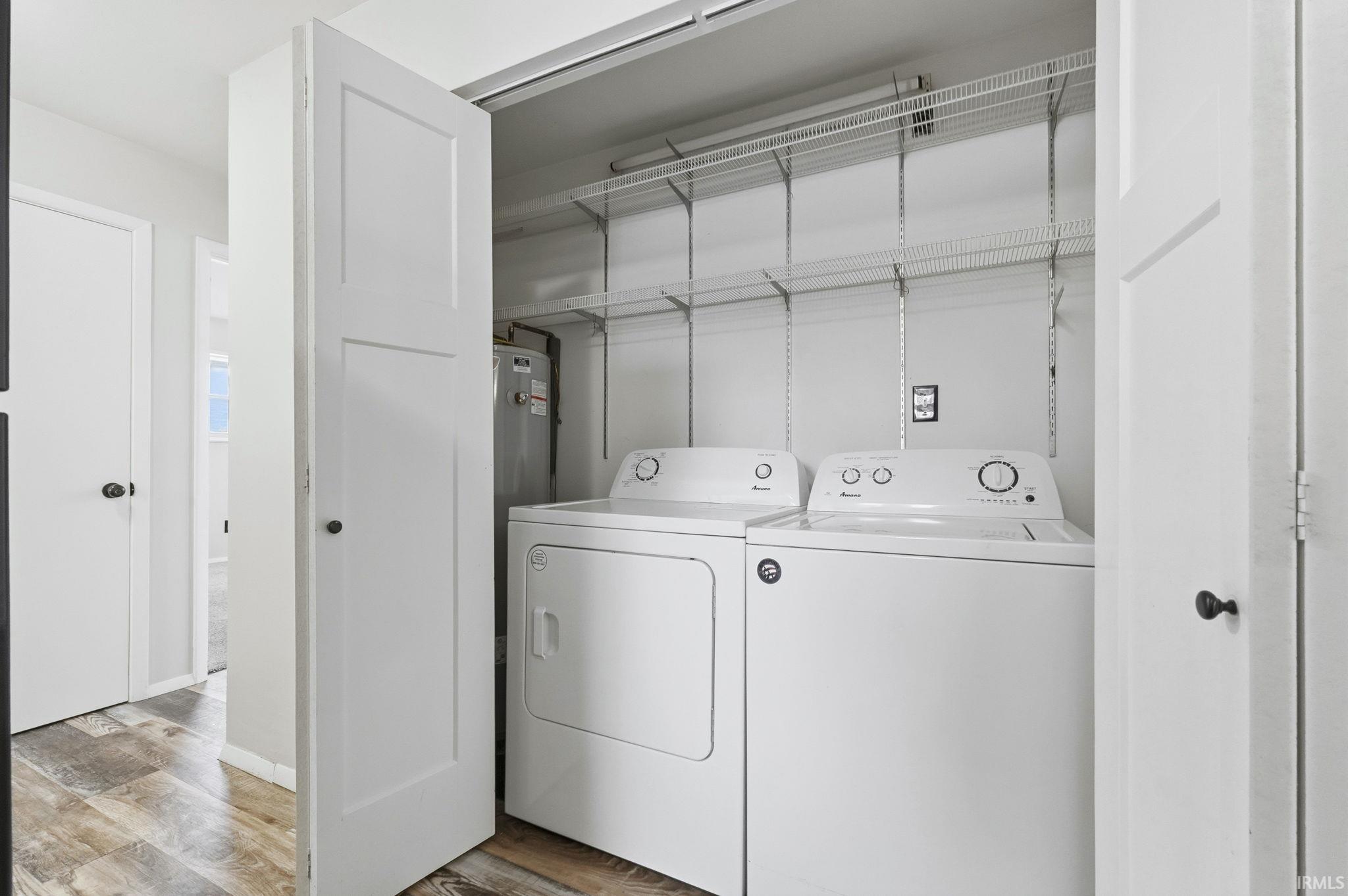 Laundry area with light wood finished floors, washer and clothes dryer, and water heater