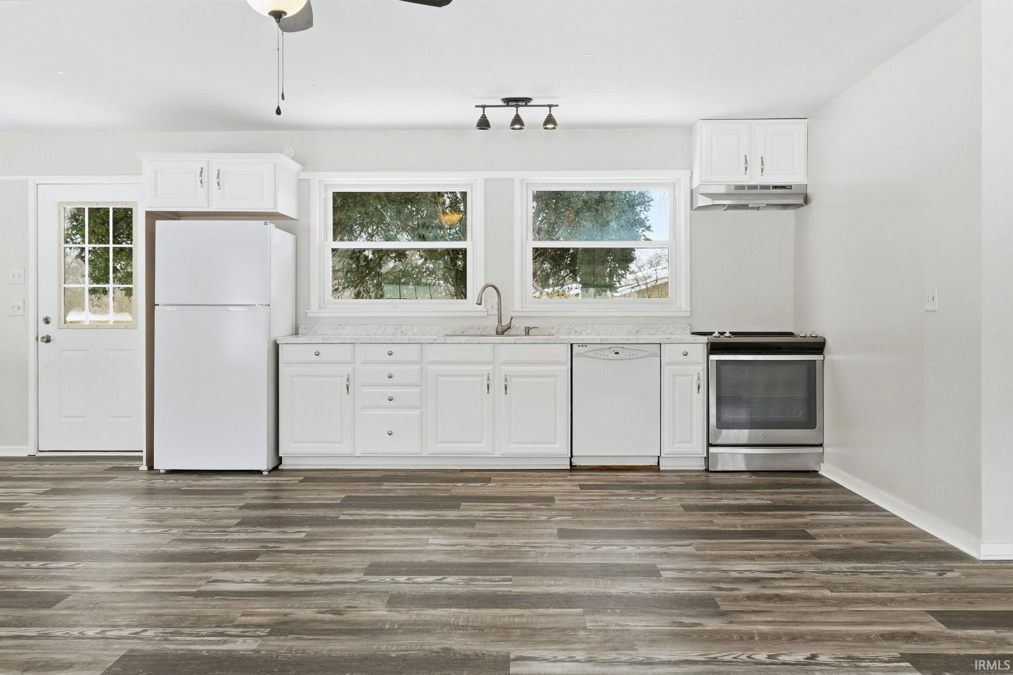Kitchen with white cabinetry, white appliances, light countertops, and ceiling fan