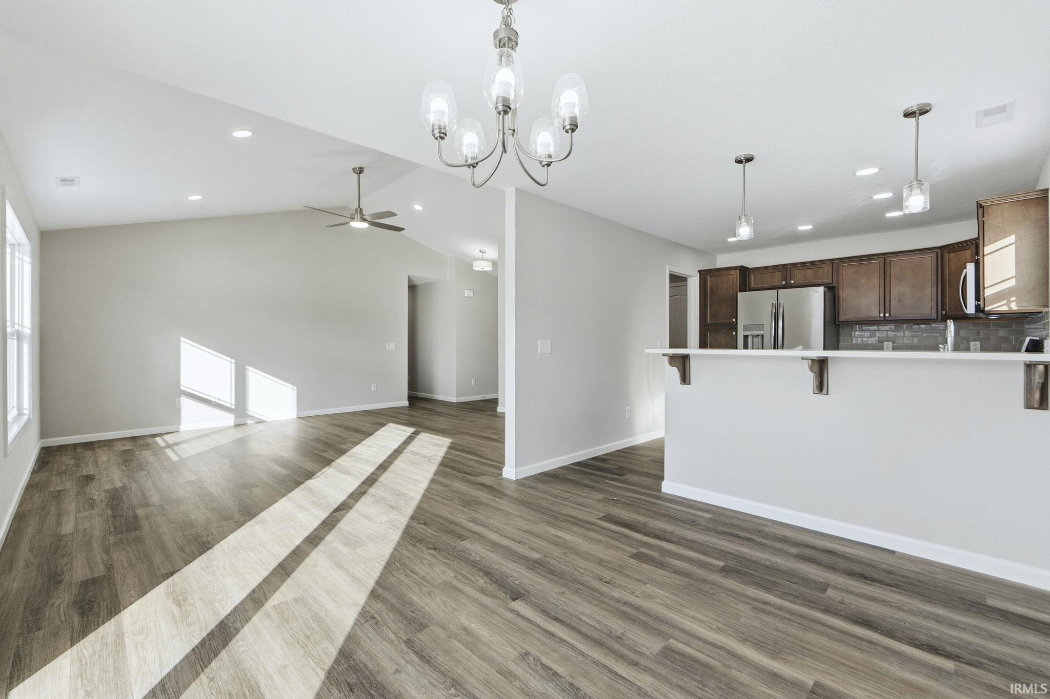 Kitchen featuring a kitchen breakfast bar, dark wood finished floors, open floor plan, stainless steel appliances, and light countertops