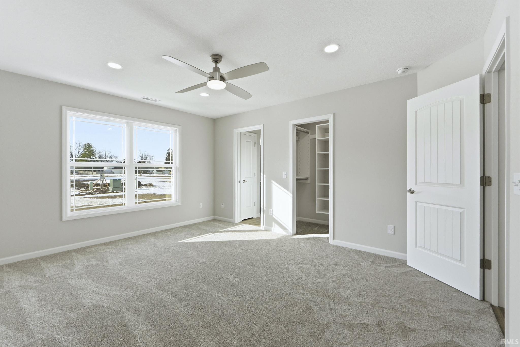 Unfurnished bedroom with a spacious closet, a ceiling fan, light colored carpet, and recessed lighting