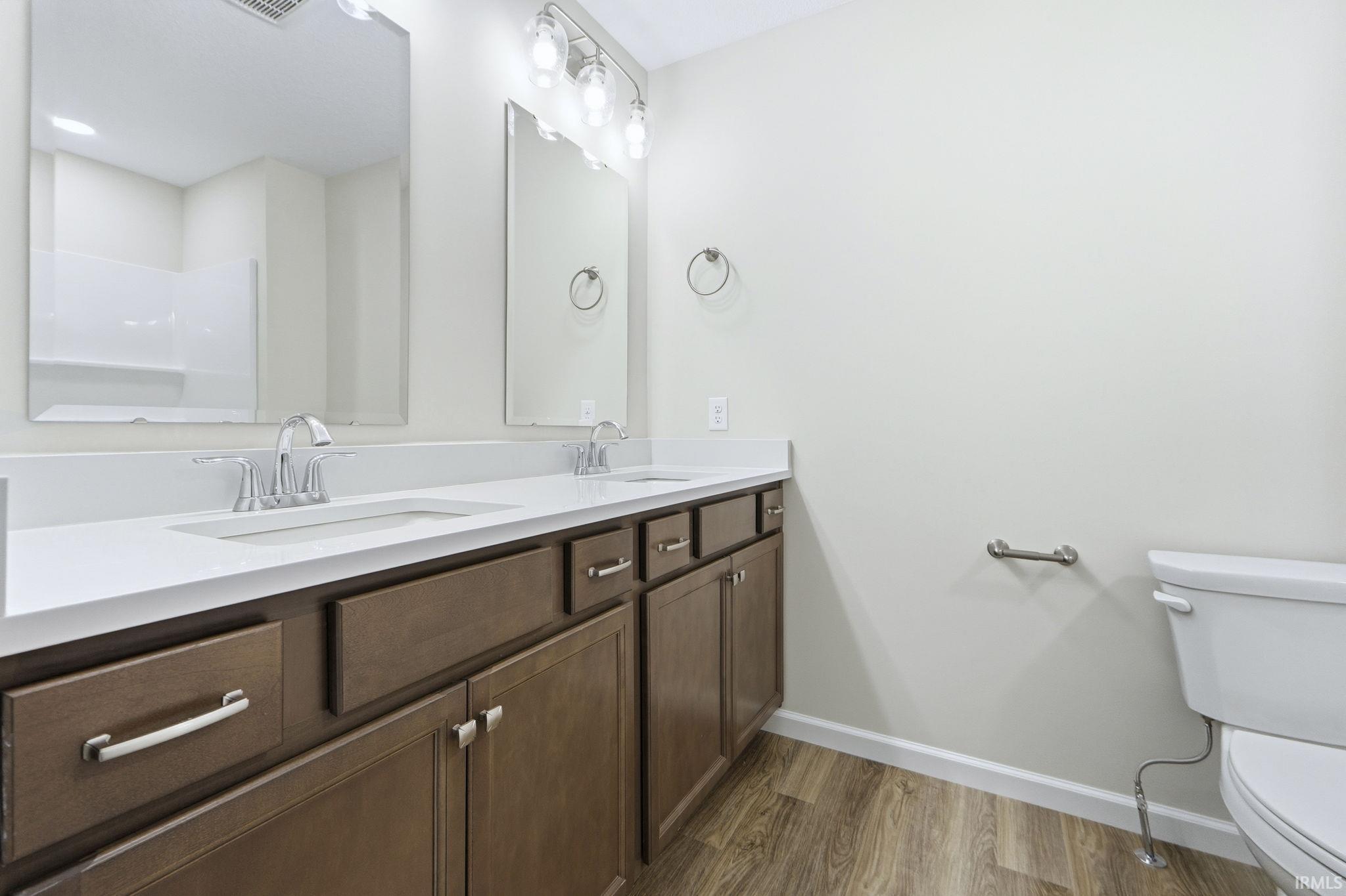 Bathroom with double vanity and light wood-style flooring