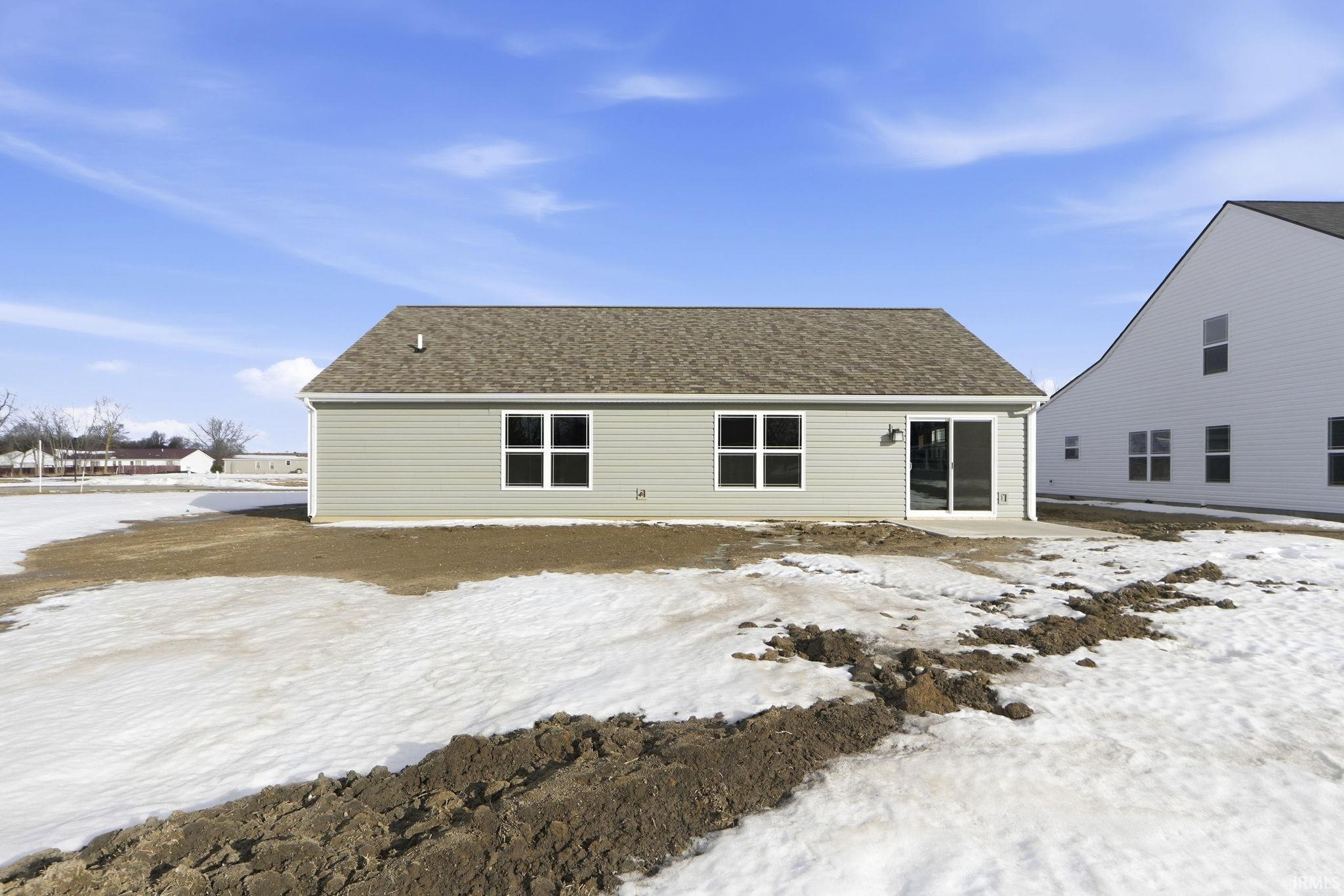 Snow covered house with a patio and roof with shingles