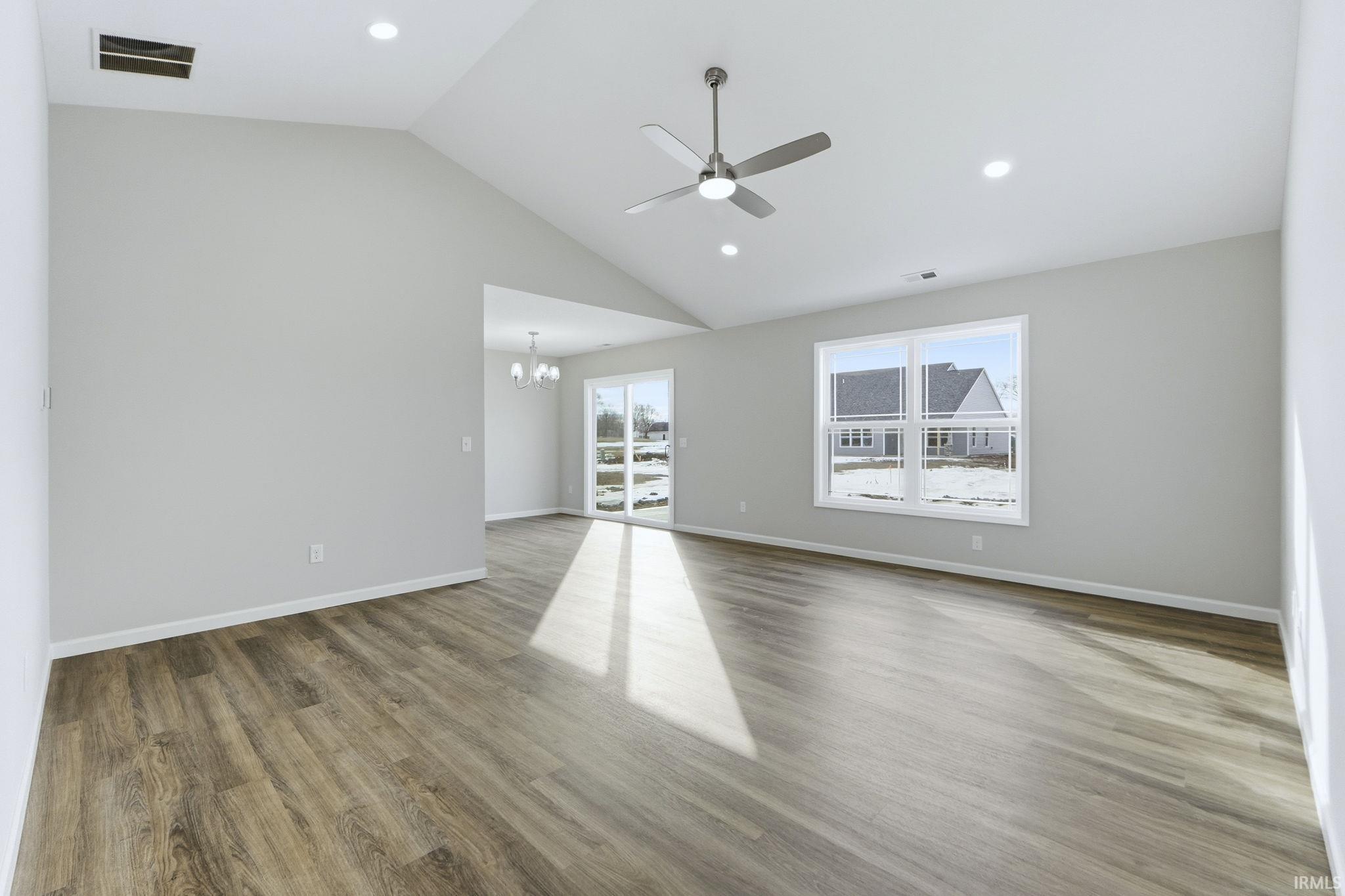 Unfurnished room with a ceiling fan, vaulted ceiling, a chandelier, and light wood finished floors