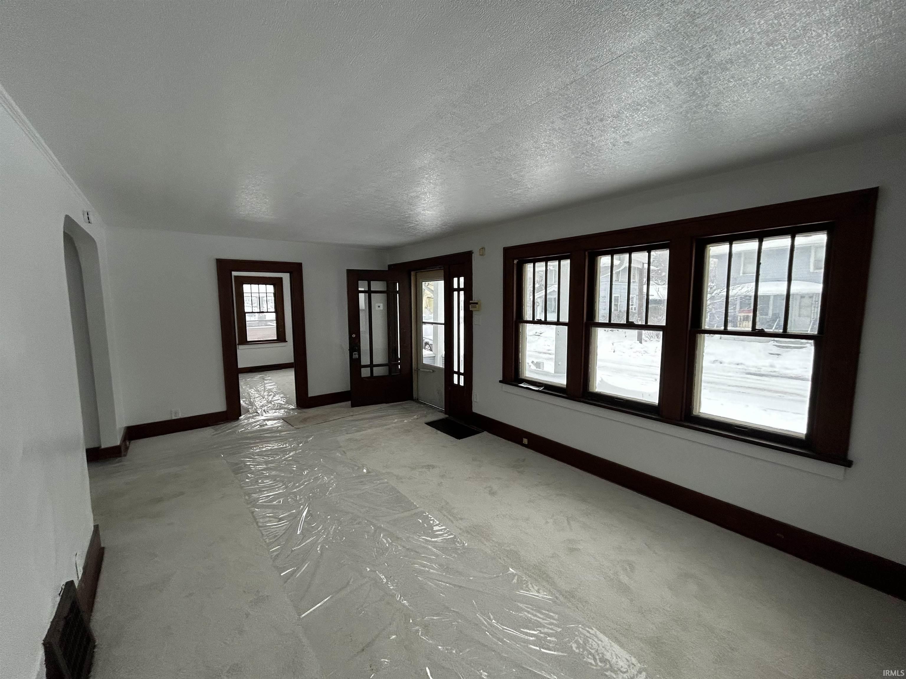 Spare room featuring carpet floors, a textured ceiling, and arched walkways