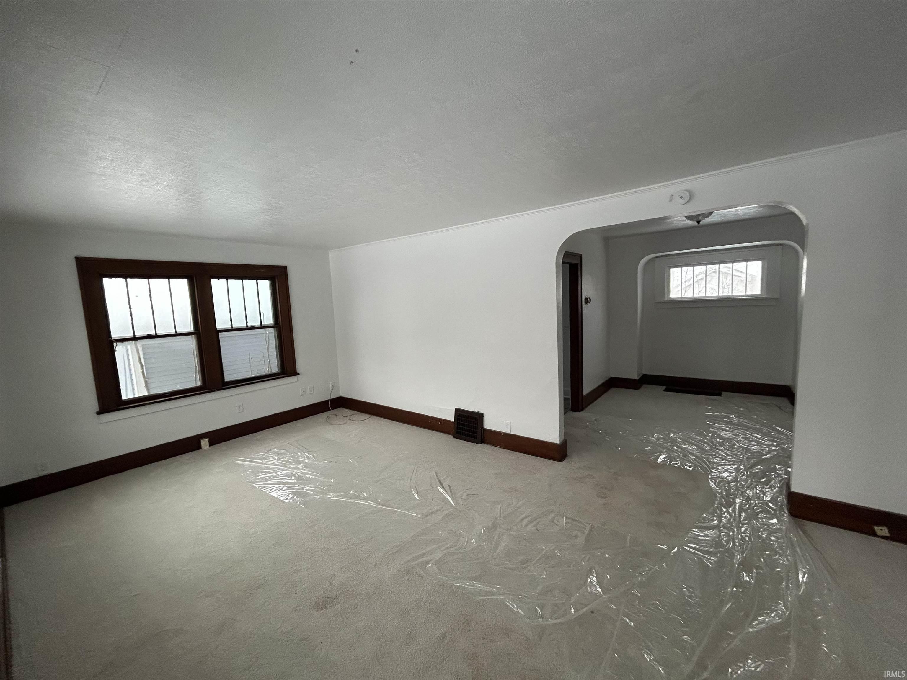 Unfurnished living room featuring arched walkways, a textured ceiling, and carpet