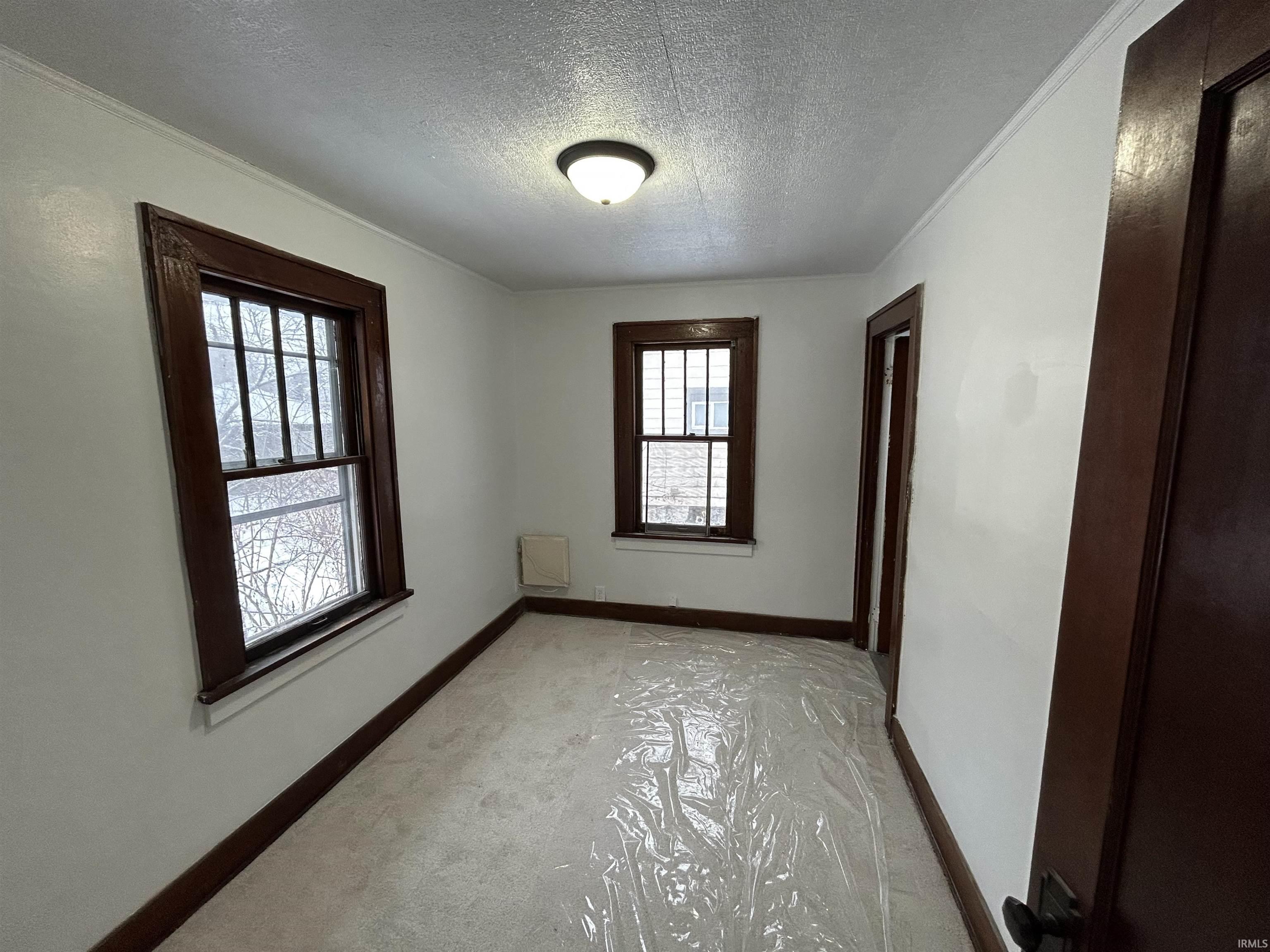 Empty room with a textured ceiling and baseboards