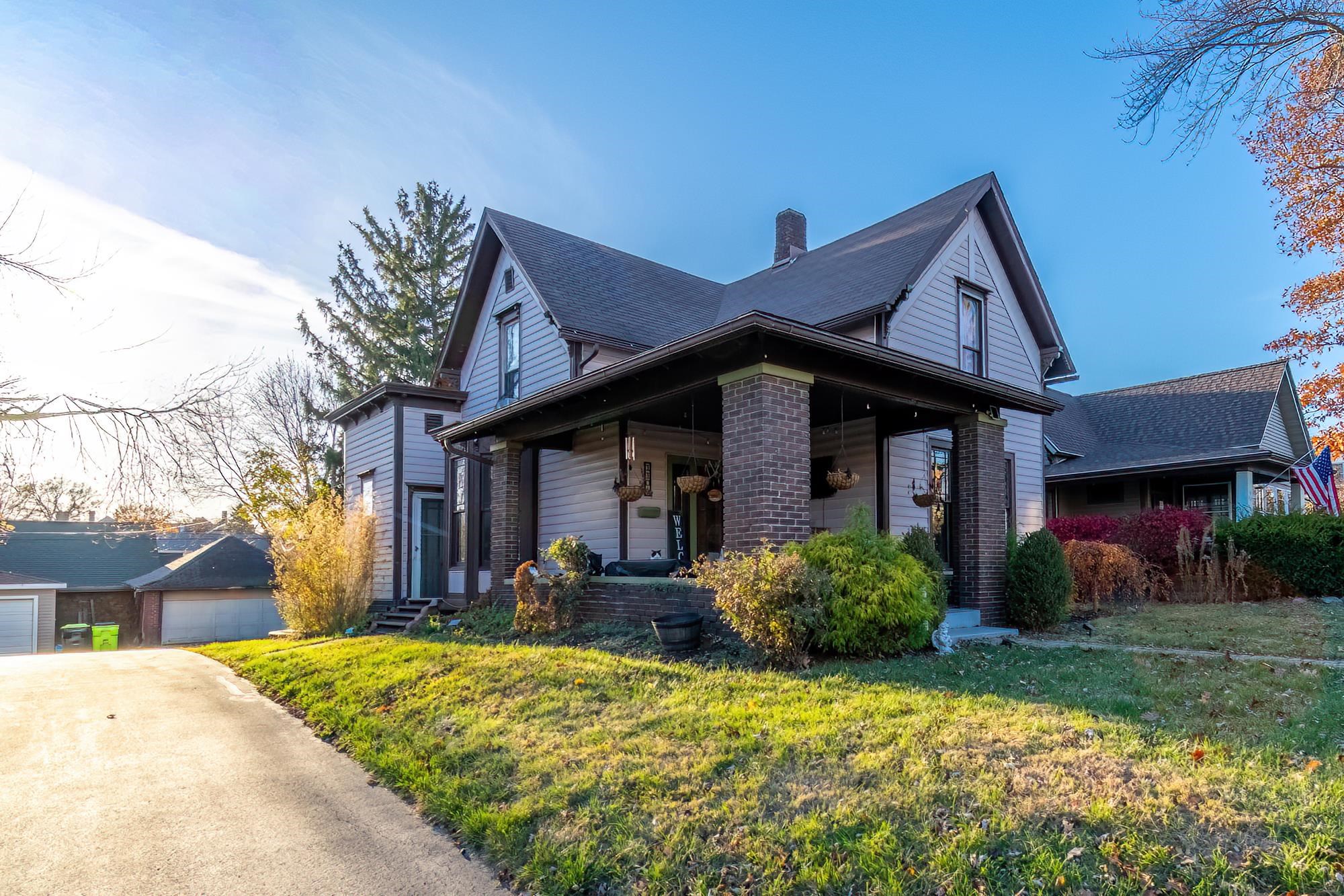 View of front of property with a chimney, a front lawn, and covered porch