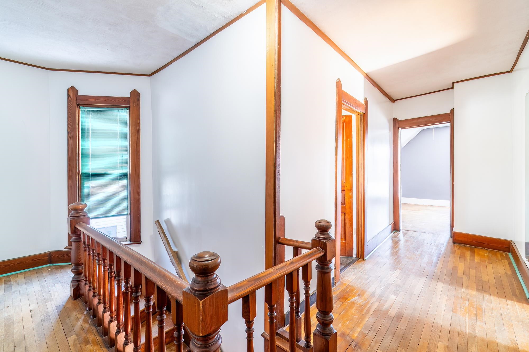 Hall with an upstairs landing, hardwood floors, and crown molding