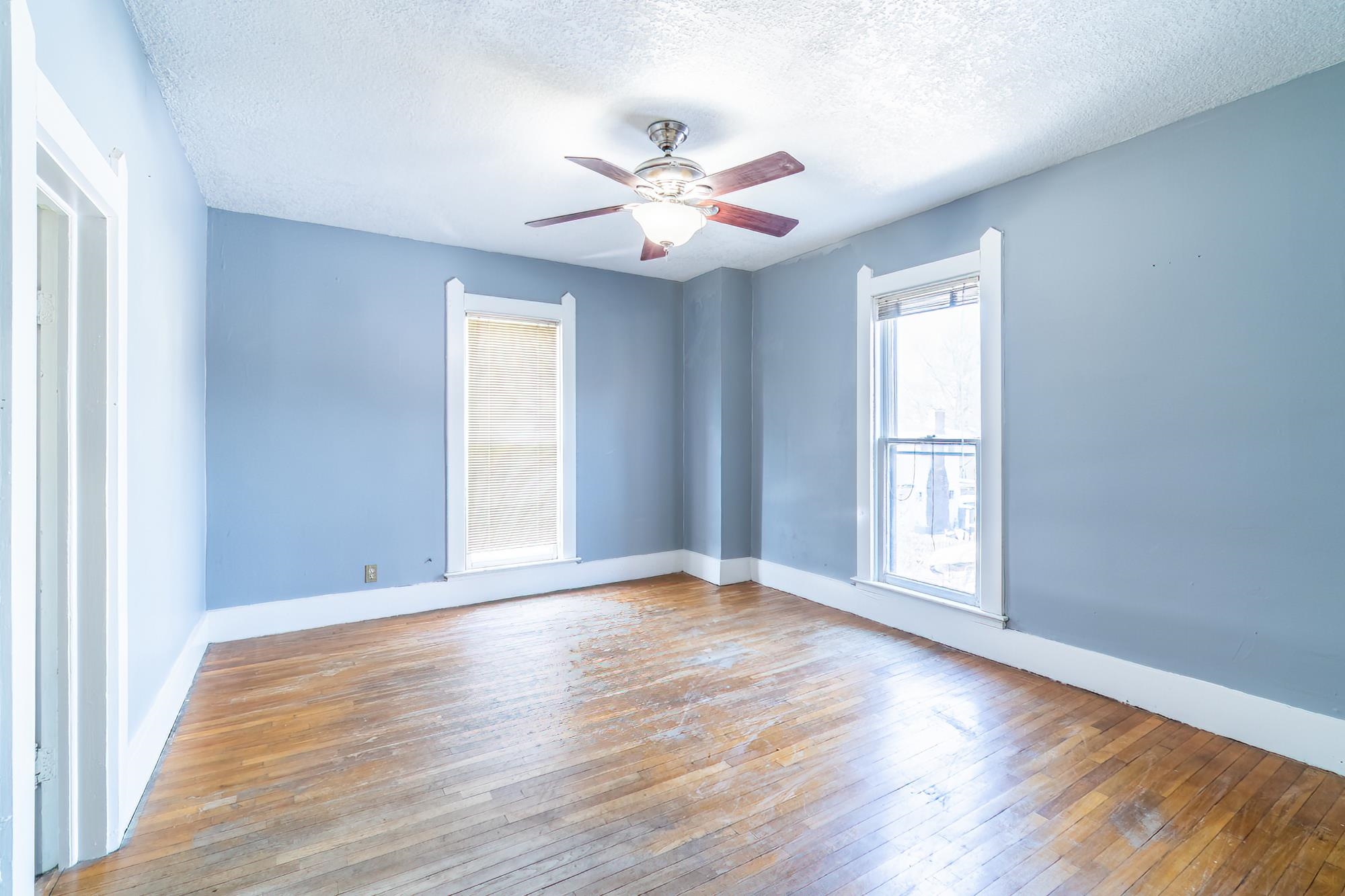 Unfurnished room featuring hardwood flooring, a ceiling fan, and a textured ceiling