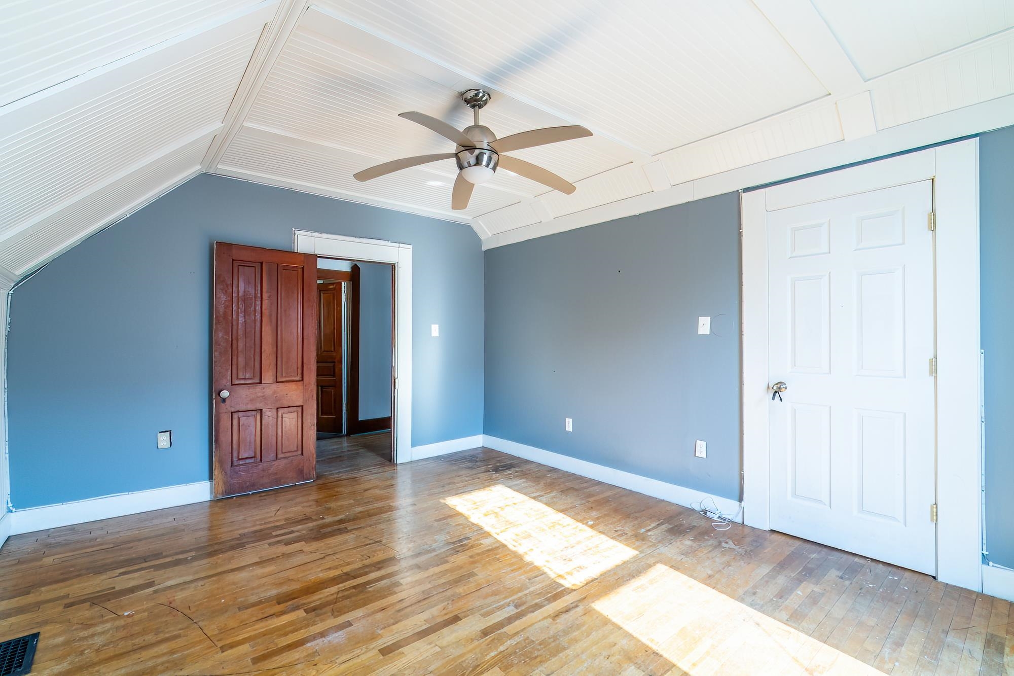 Bedroom with hardwood floors, ceiling fan, and lofted ceiling