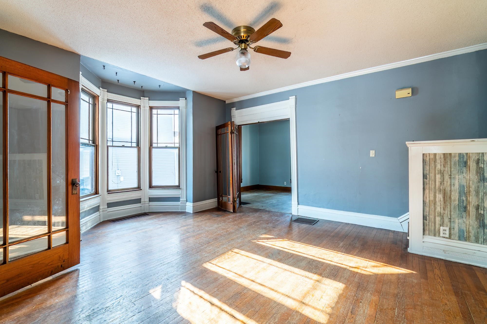 Unfurnished room with hardwood flooring and ceiling fan