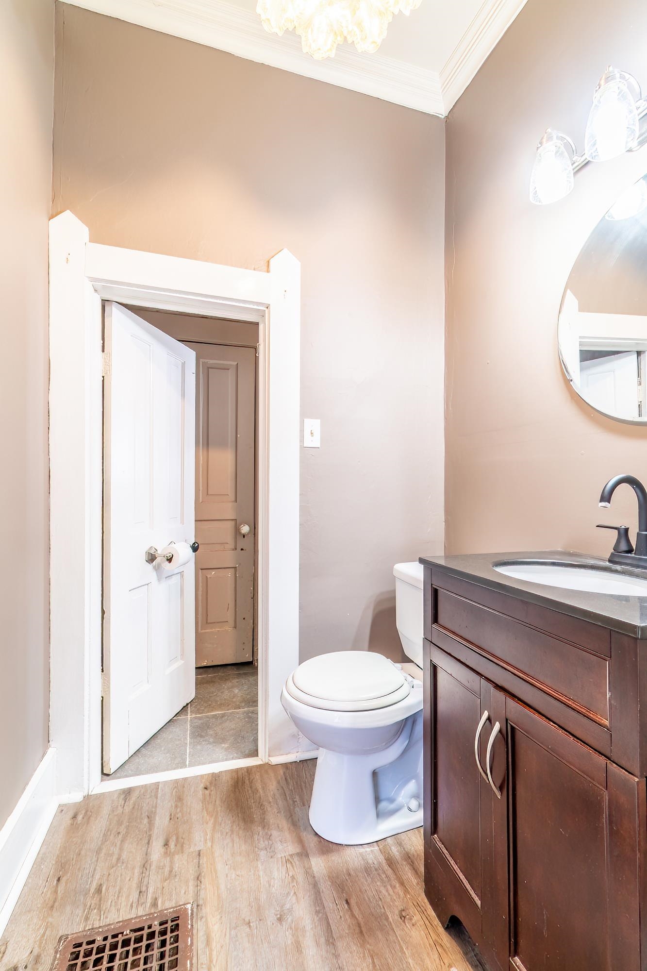 Half bathroom with vanity, light wood-type flooring, and crown molding