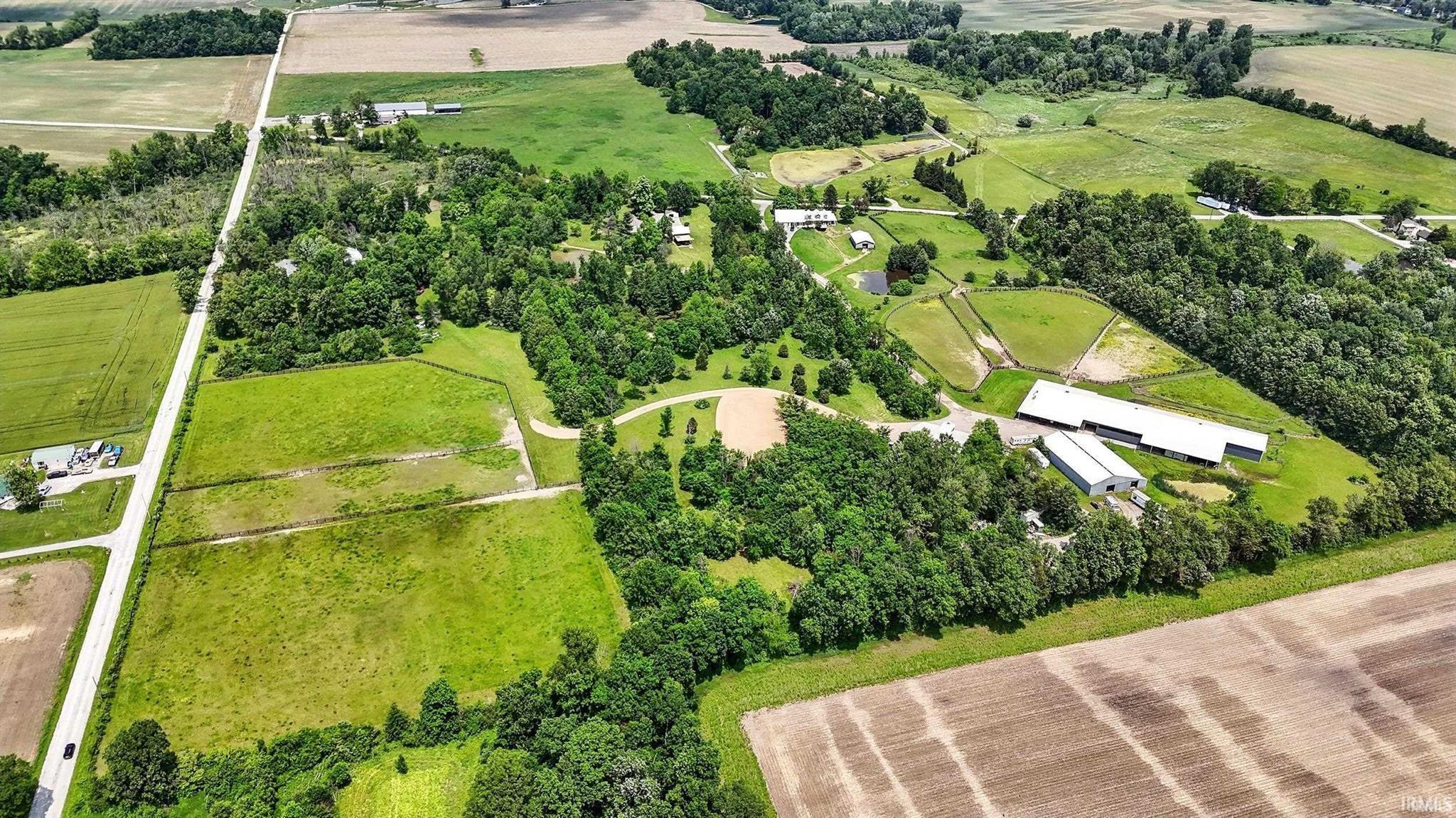Overview of rural landscape featuring large plots for crops and a tree filled landscape