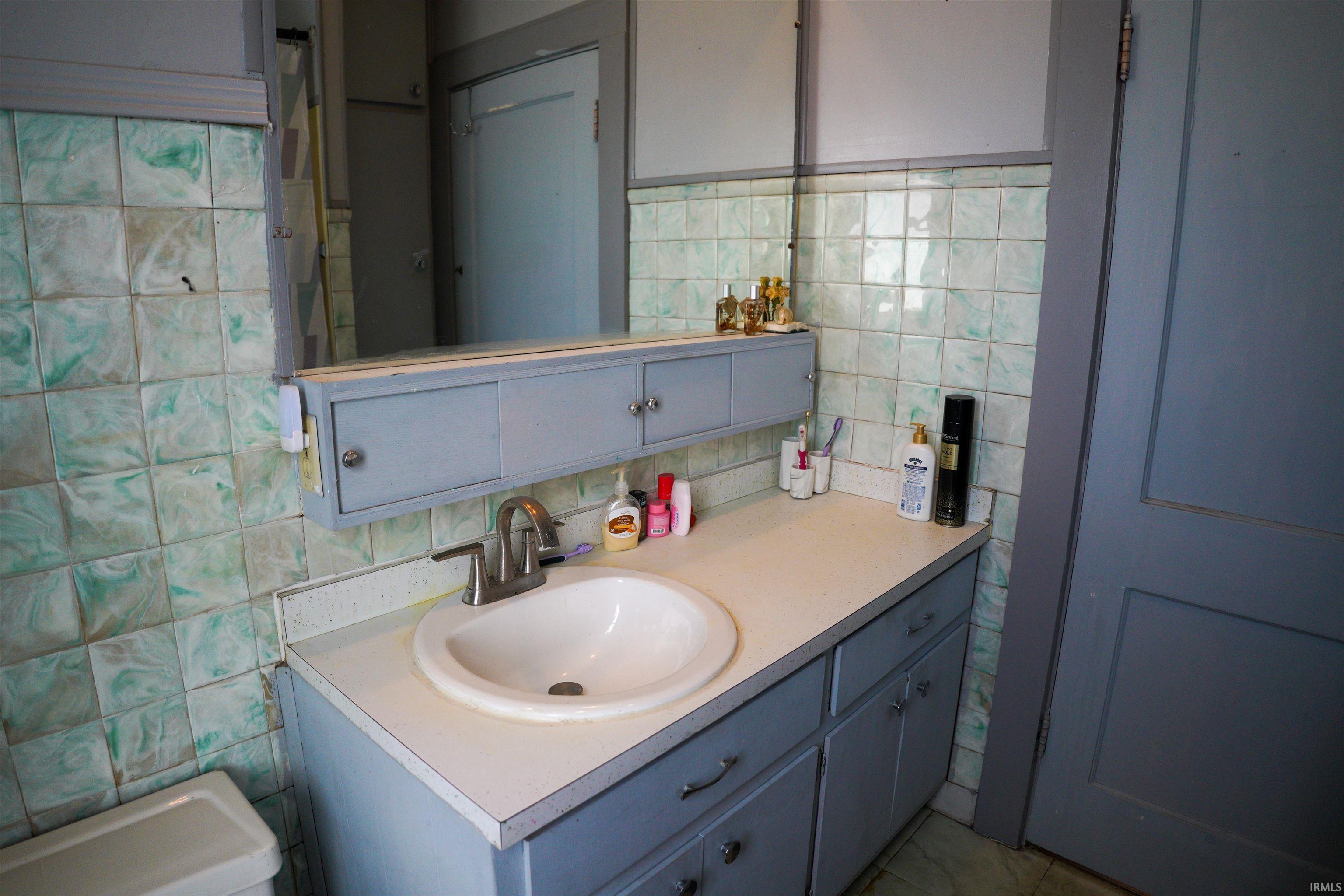 Bathroom with tile walls, vanity, backsplash, and a shower with shower curtain