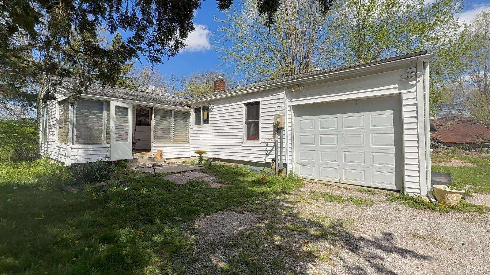 Single-story residence featuring white siding and an attached garage with a panel door
