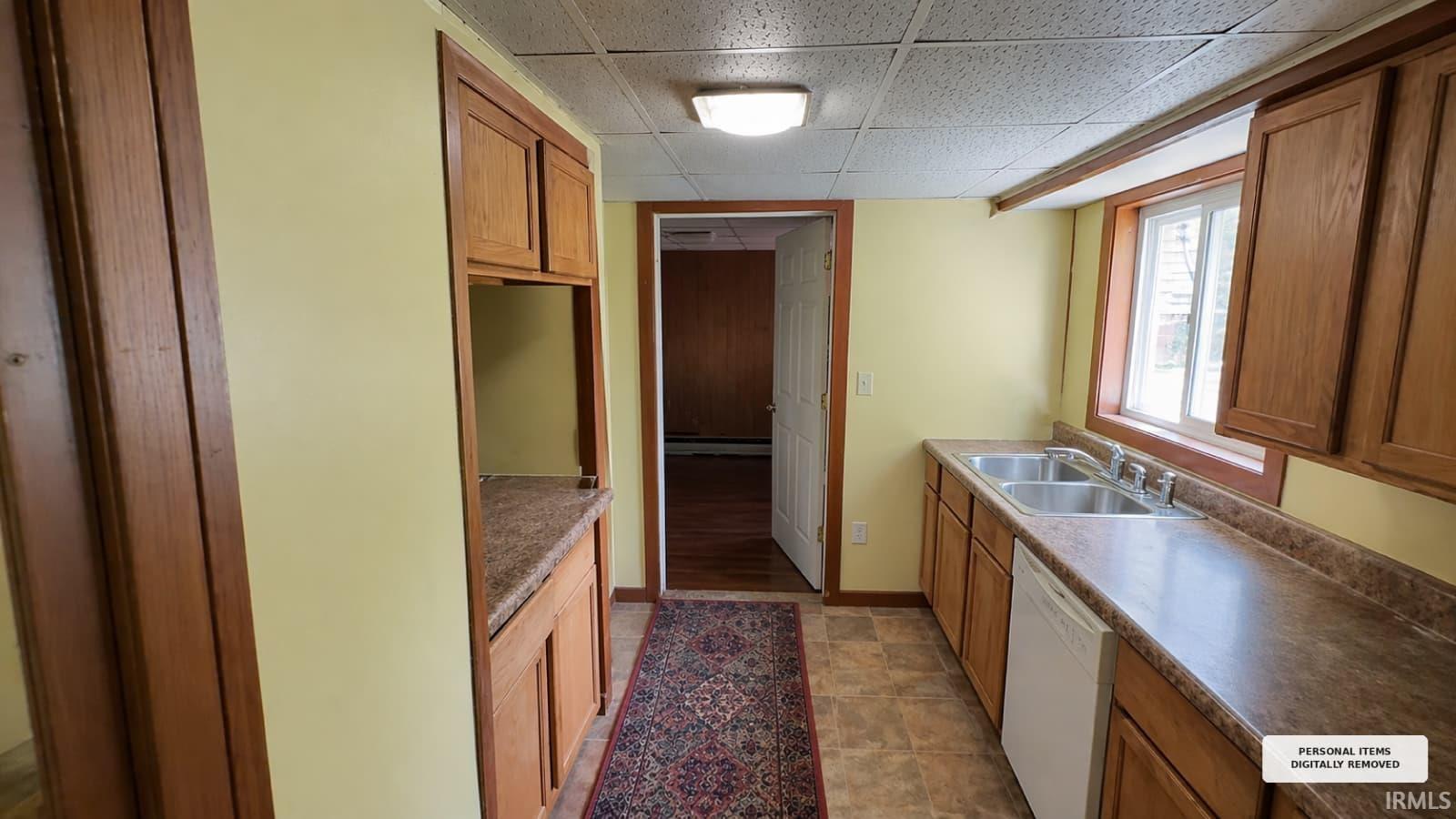 Kitchen featuring wood cabinetry, laminate countertops, a double basin stainless steel sink, and a built-in dishwasher