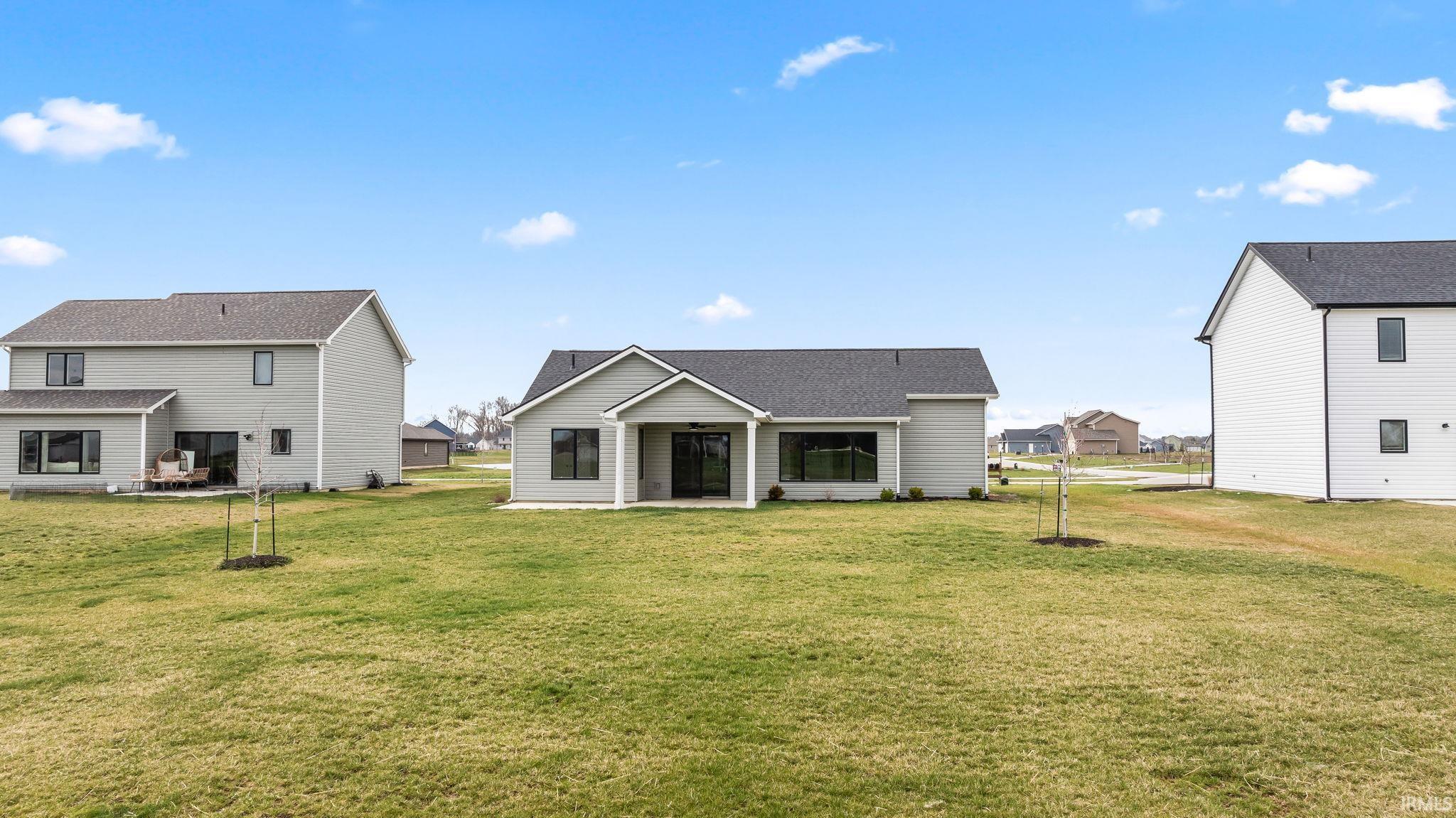 Back of property with a patio area, a yard, a shingled roof, and a residential view
