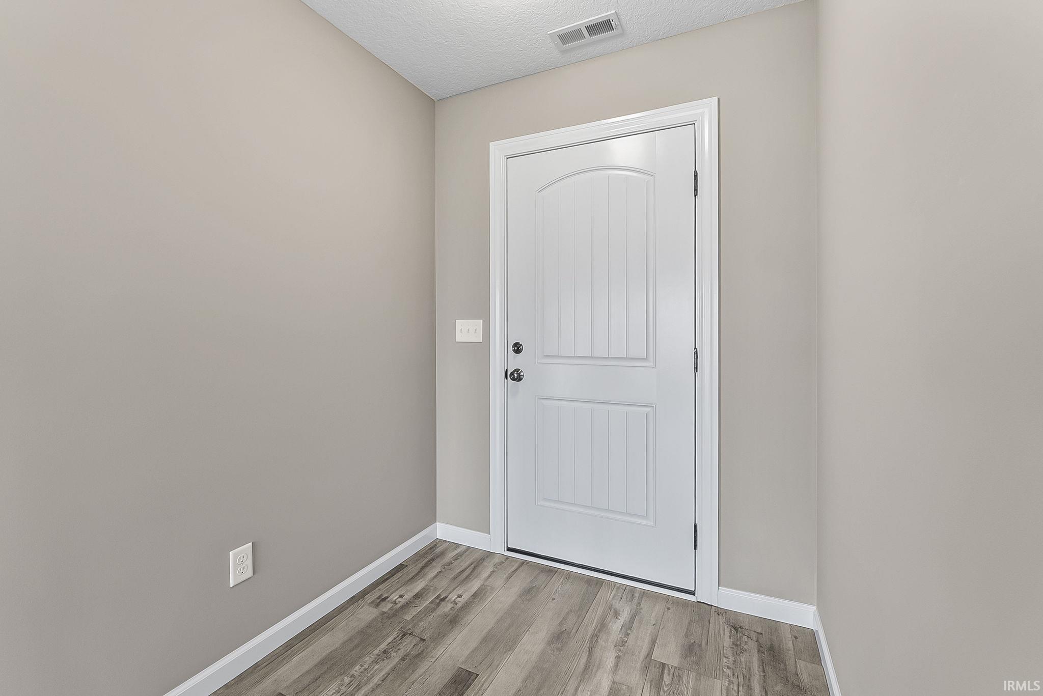 Doorway to outside featuring wood finished floors and a textured ceiling