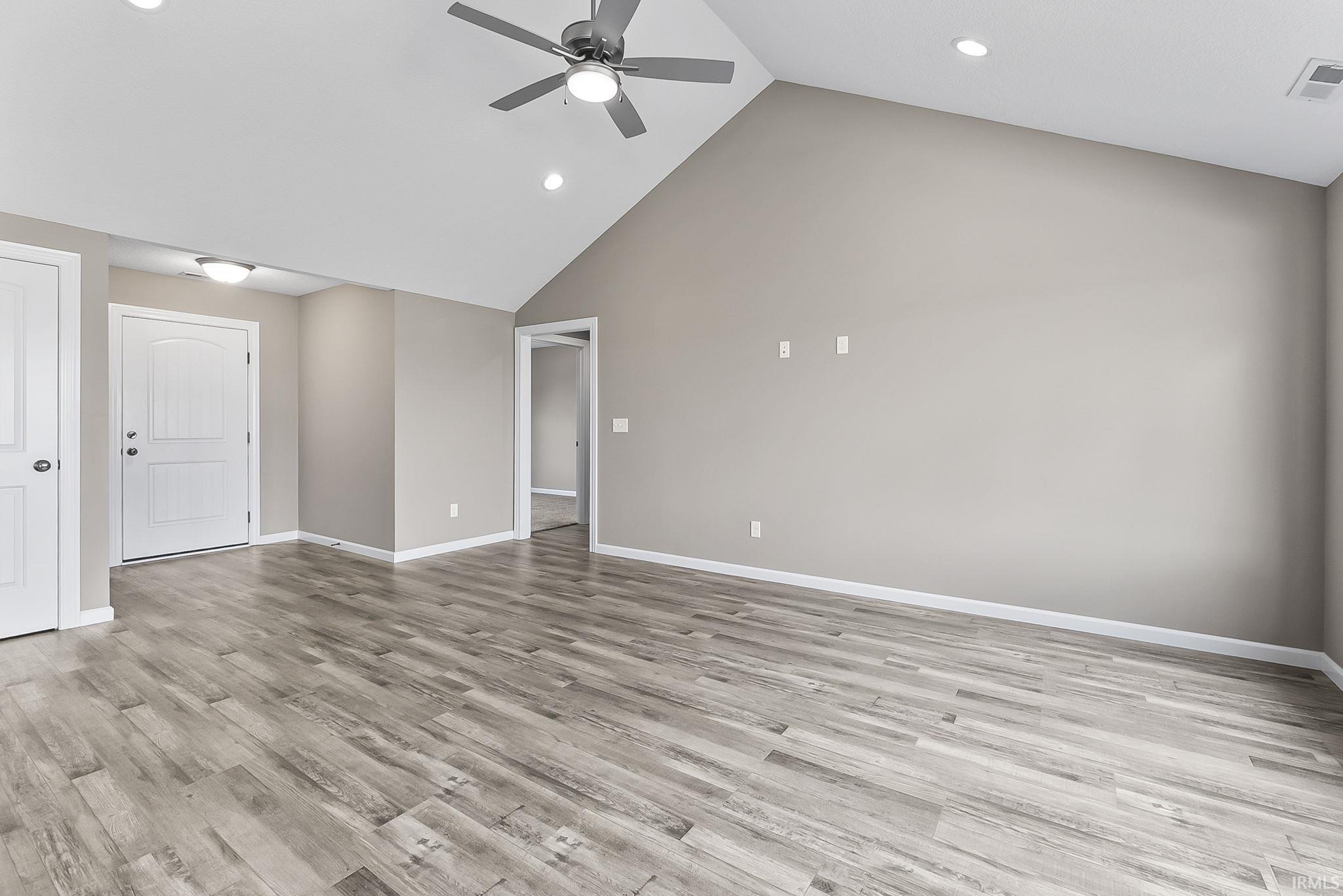 Empty room with a ceiling fan, recessed lighting, a high ceiling, and light wood-style flooring