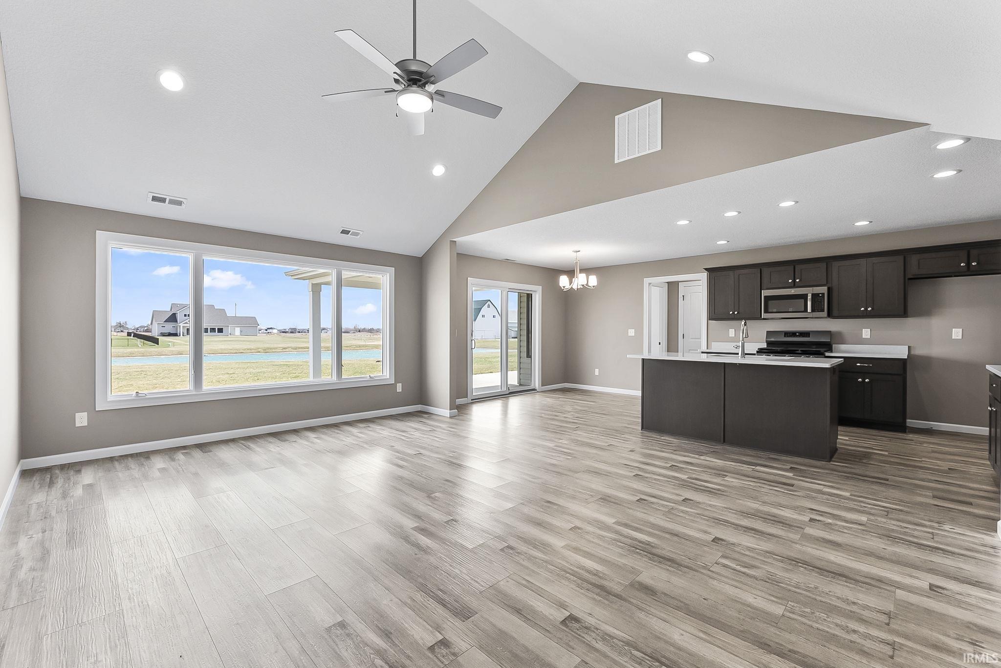 Kitchen featuring a ceiling fan, open floor plan, a high ceiling, light countertops, and hanging lights
