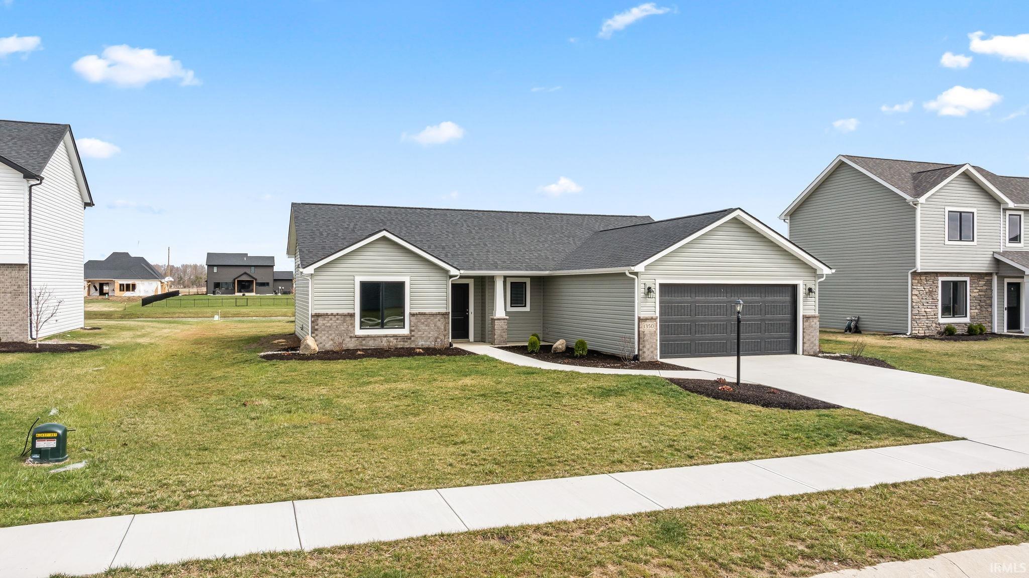 View of front of house with brick siding, a garage, concrete driveway, a front yard, and a shingled roof